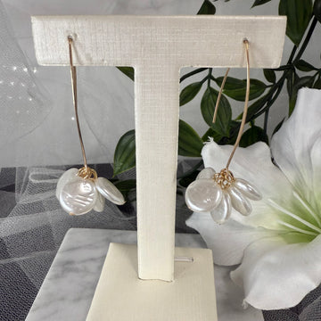Pair of earrings on a white stand with a floral background