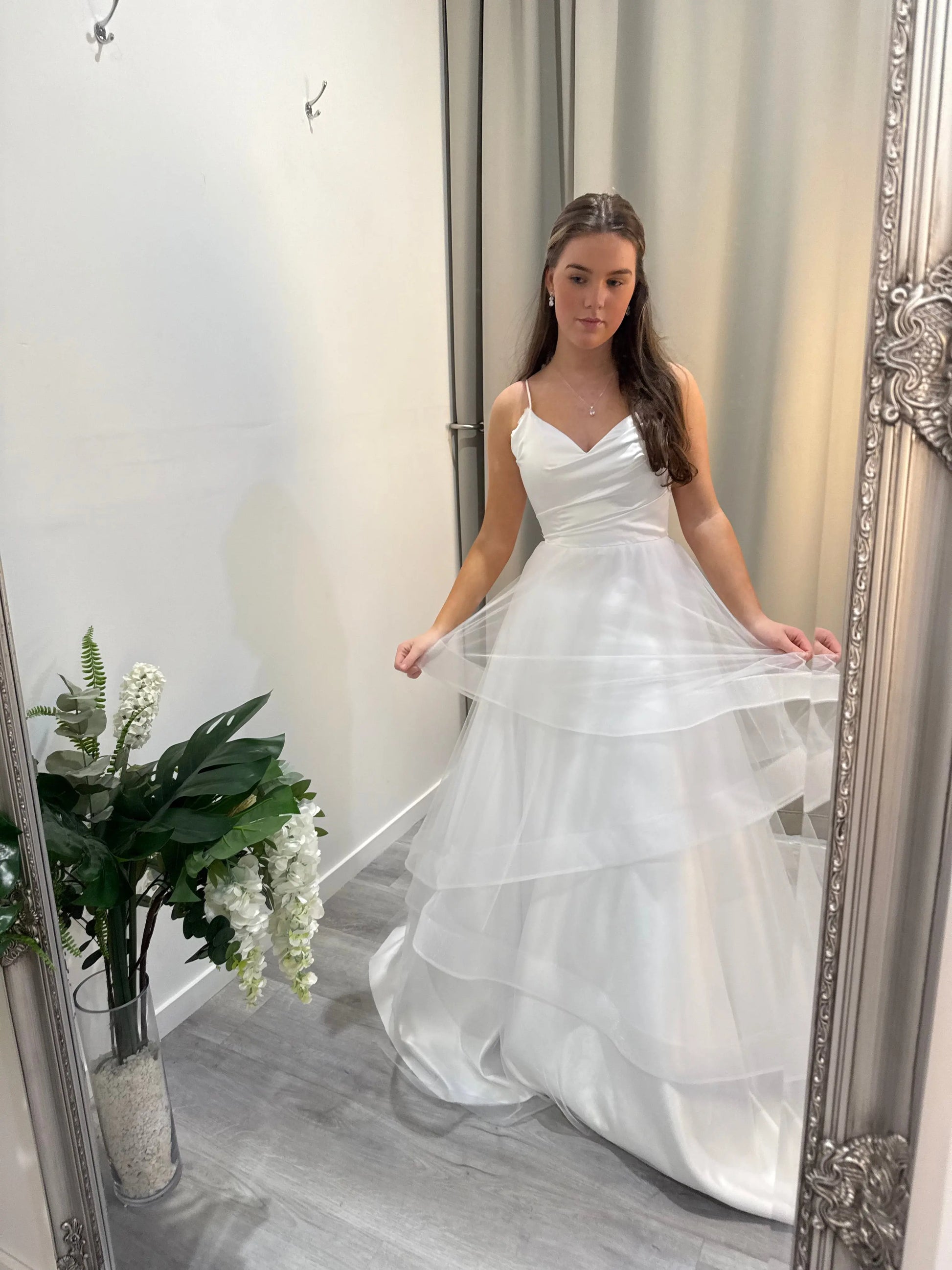 Model looking into the mirror, lifting the layered tulle skirt to reveal soft fabric details