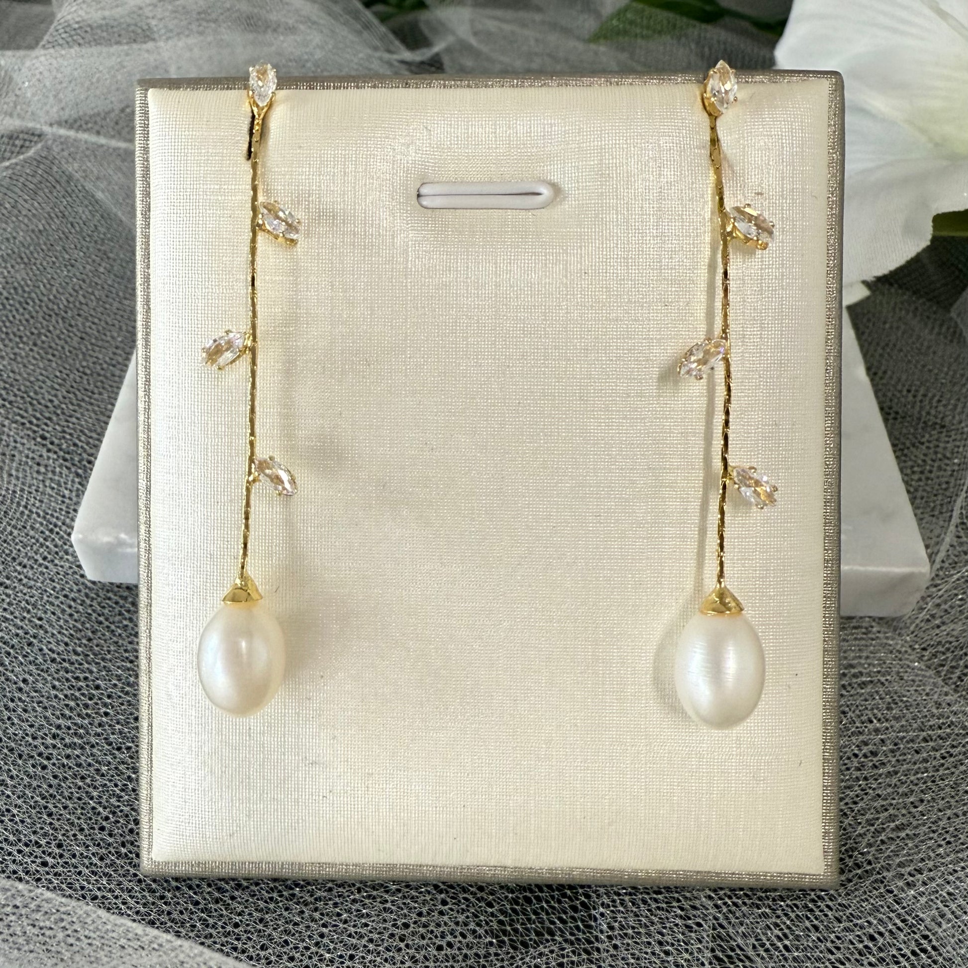 Pair of pearl earrings on a display card with a textured surface background