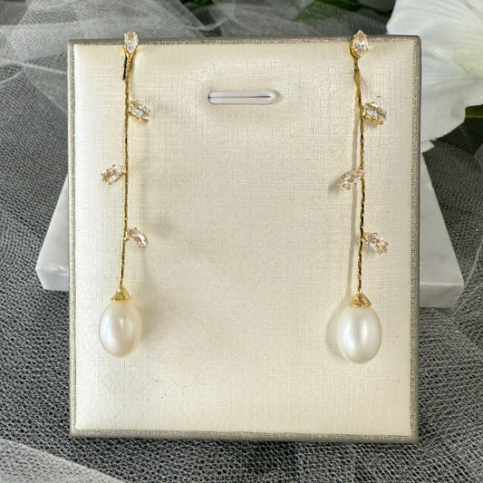 Pair of pearl earrings on a display card with a textured surface background