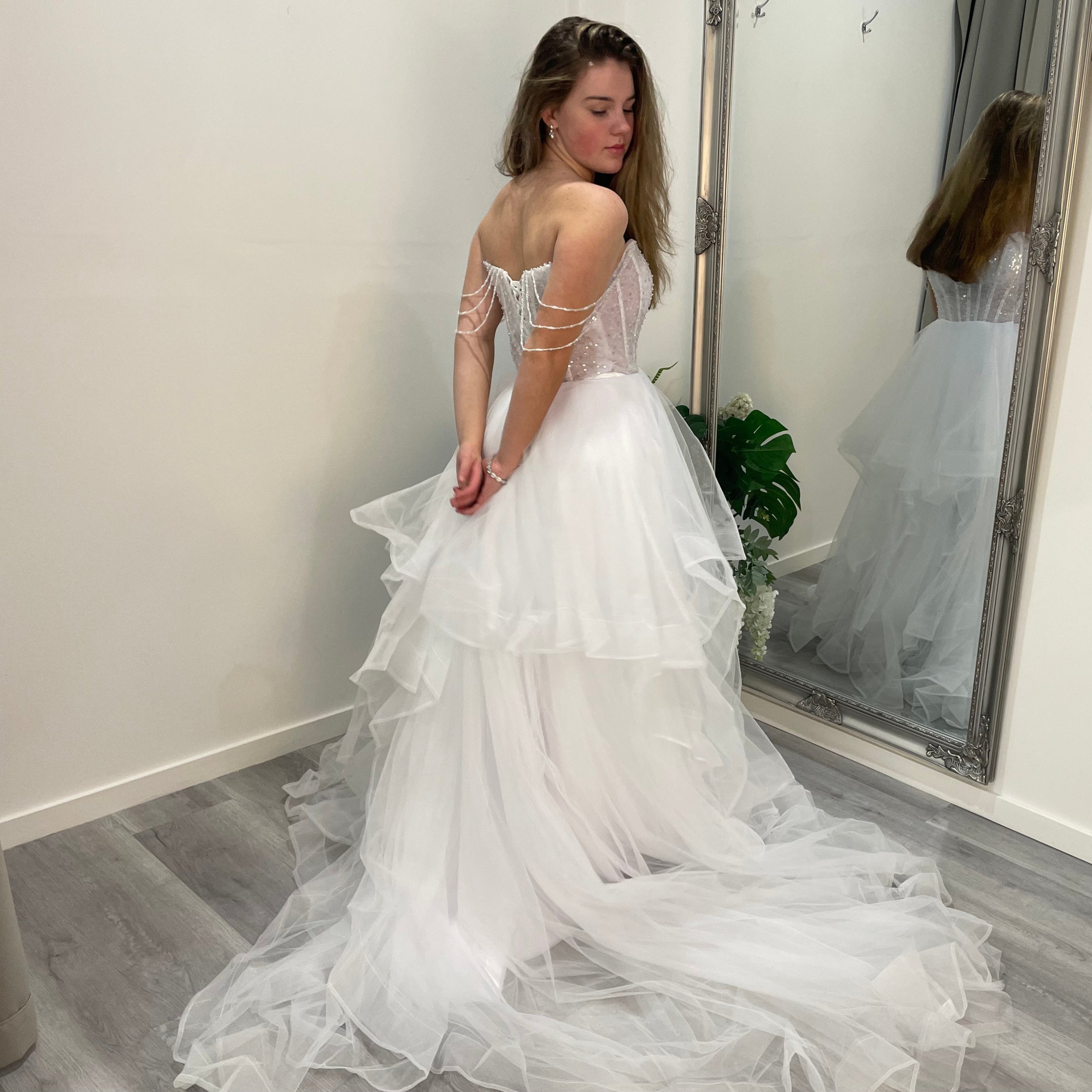 Side back view of Elowen Debutante Dress highlighting the beaded corset bodice and tulle A-line skirt with soft, elegant ruffles at the waist.