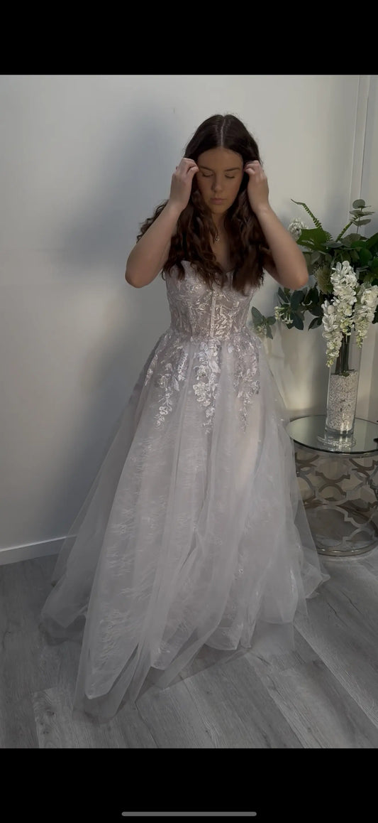 Woman in a sparkling silver dress standing in front of the camera, showing the front of the dress