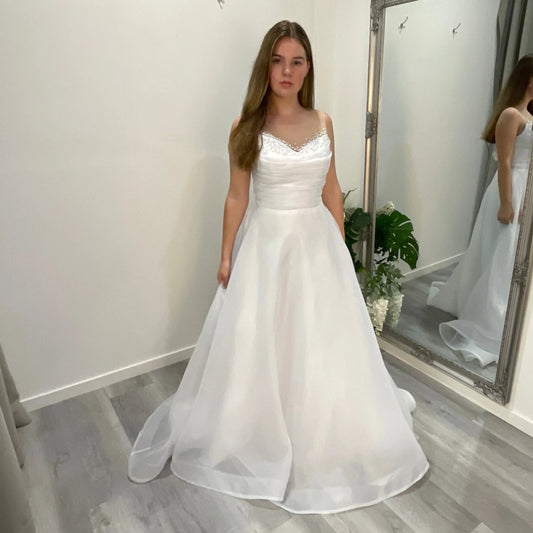 Front view of Starlit Debutante Dress featuring a sweetheart neckline adorned with Ilosian pearl embellishments, with an organza draping just under the neckline and a pleated A-line organza skirt.