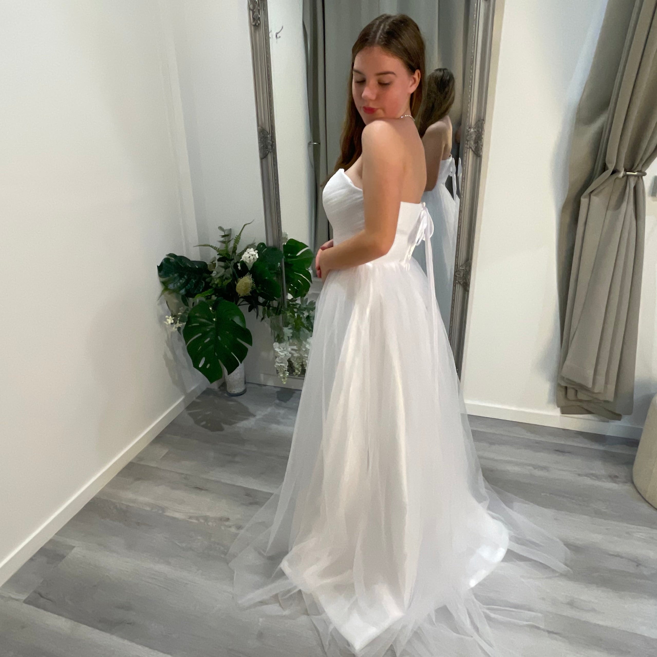 Side view of Velora Debutante Dress highlighting the lace corset bodice and the elegant A-line satin skirt with pleats, accentuating the dress's graceful flow and silhouette.