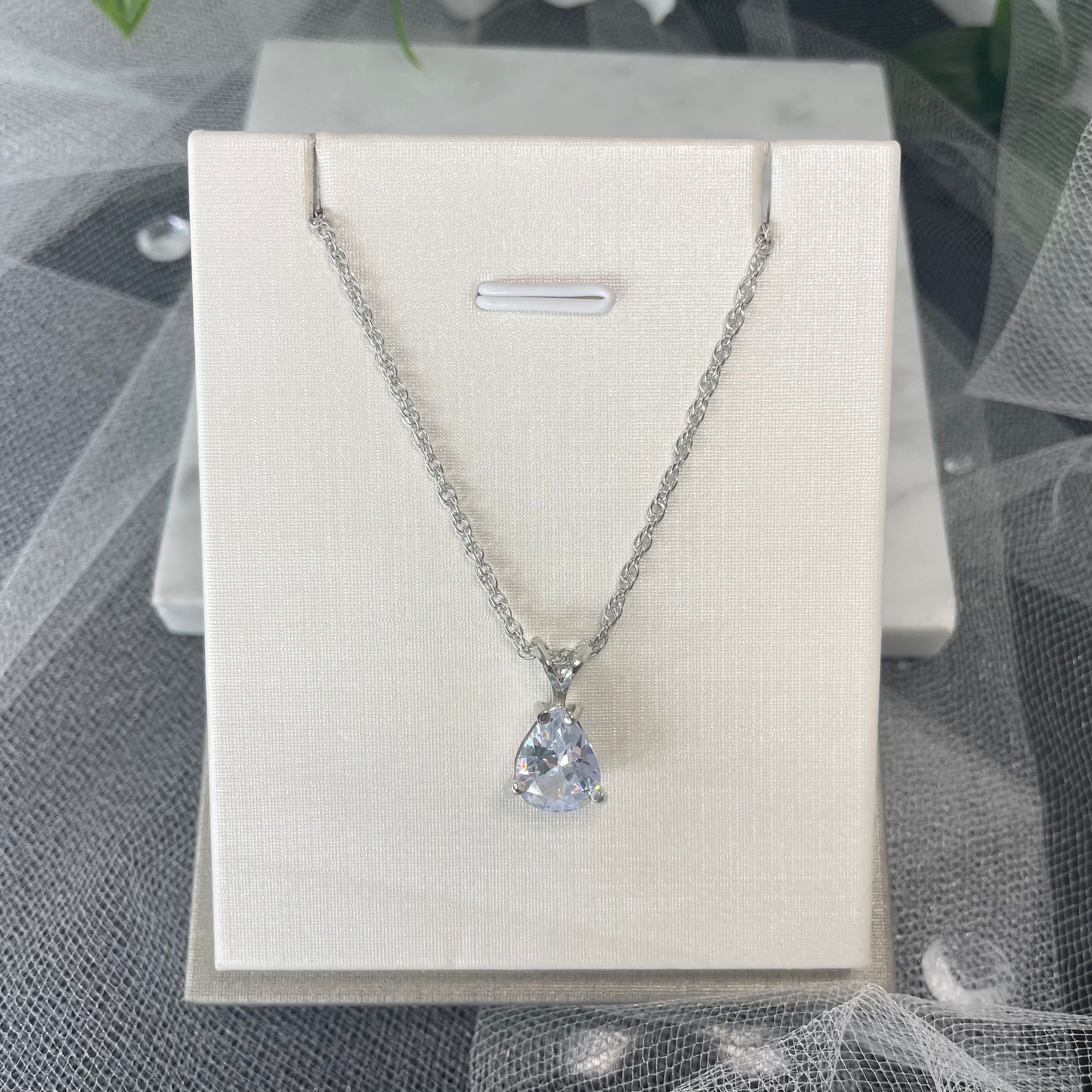 Eliana silver plated necklace with a teardrop cubic glass diamond pendant held by a 'V' silver fixture on a double cross chain.