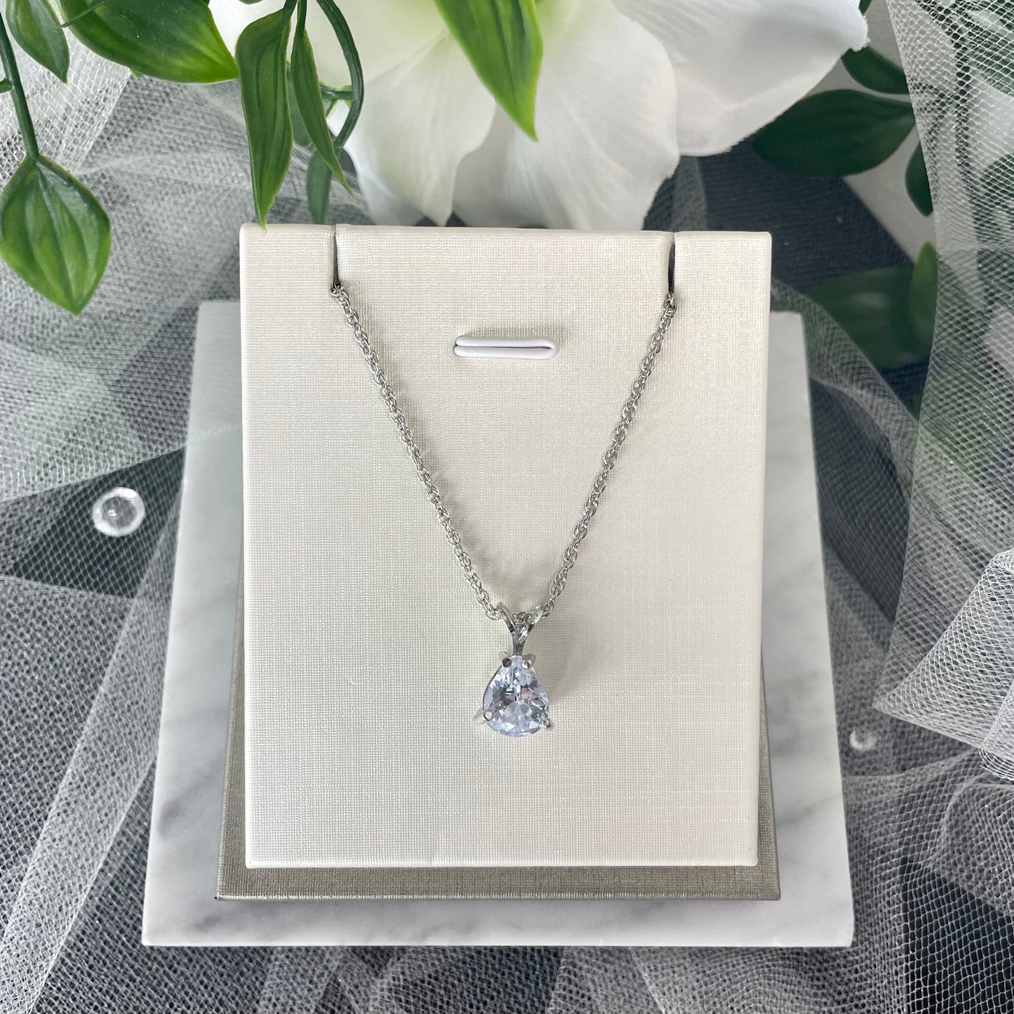 Eliana silver plated necklace with a teardrop cubic glass diamond pendant held by a 'V' silver fixture on a double cross chain.