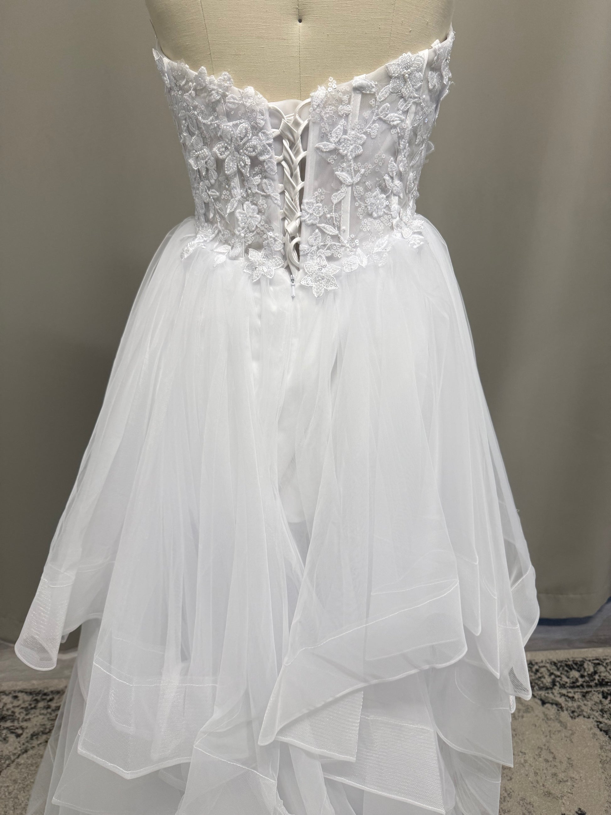 Abby V1 sheer corset debutante dress back view showing lace-up corset, floral lace and full white ruffle skirt