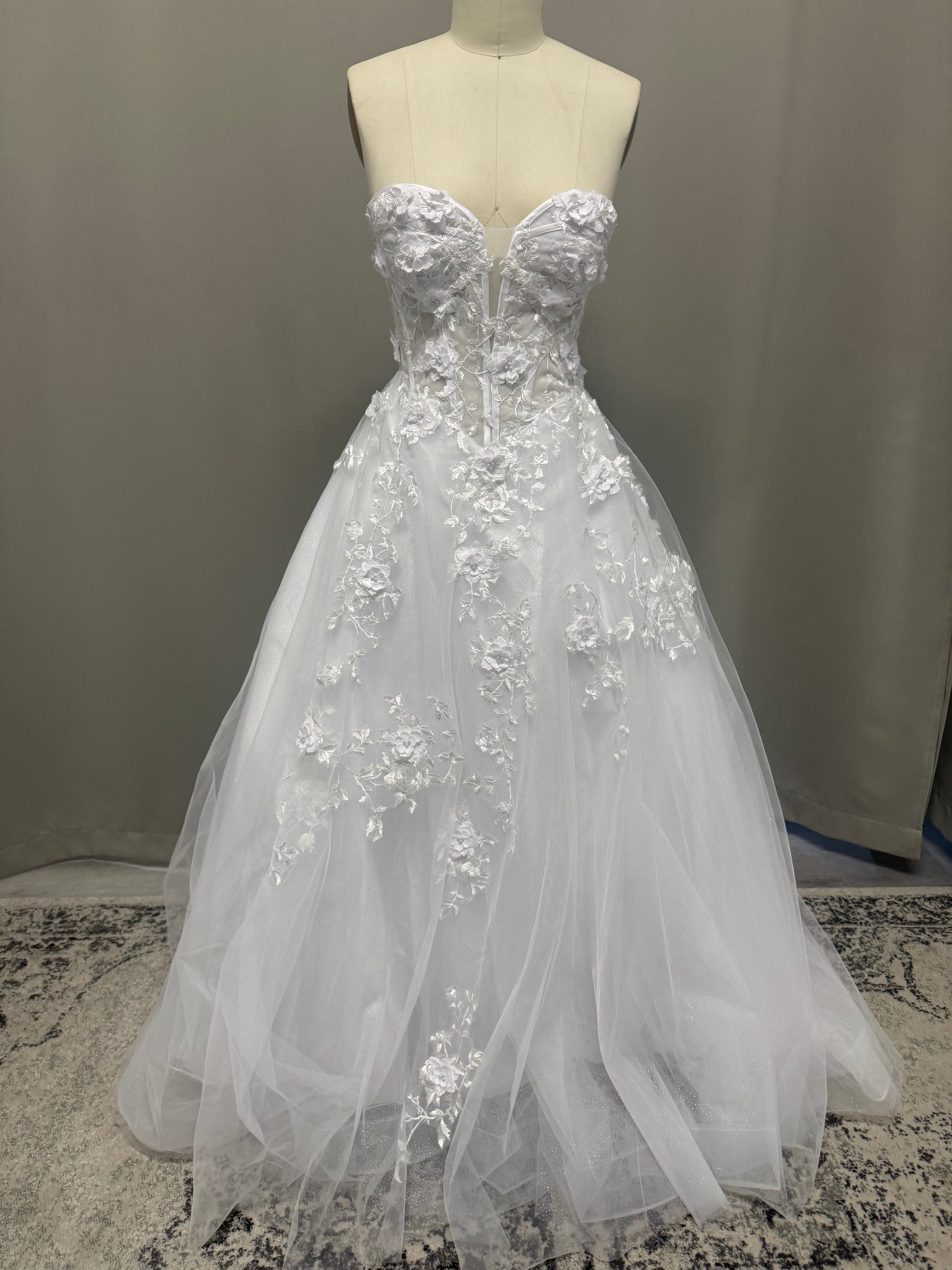 Alana V1 white 3D floral debutante dress, front view on mannequin with raised flower corset and cascading lace tulle skirt