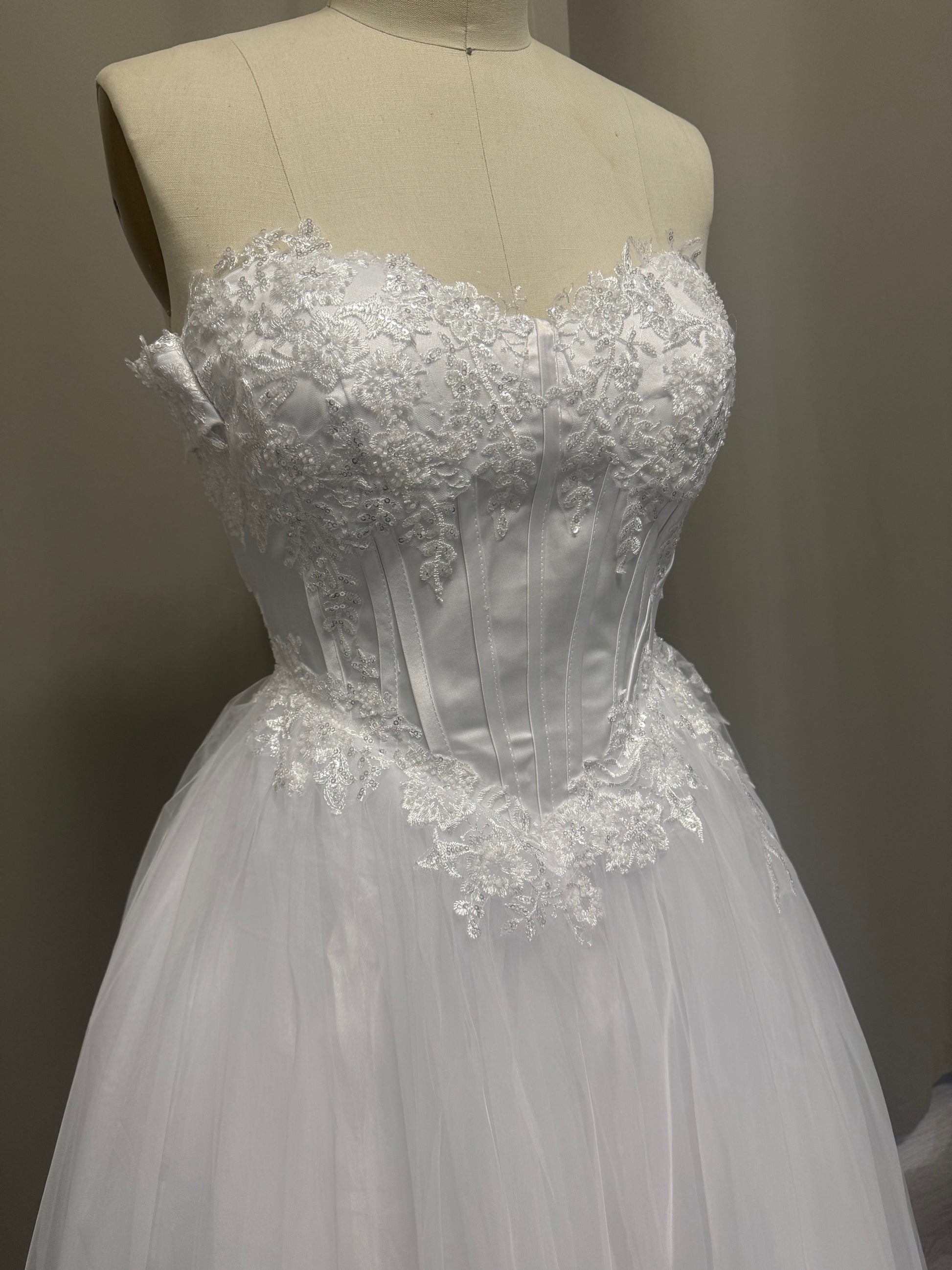 Close-up of Alex deb ball dress strapless sweetheart bodice with floral lace appliqué, sequin detail and satin corset boning