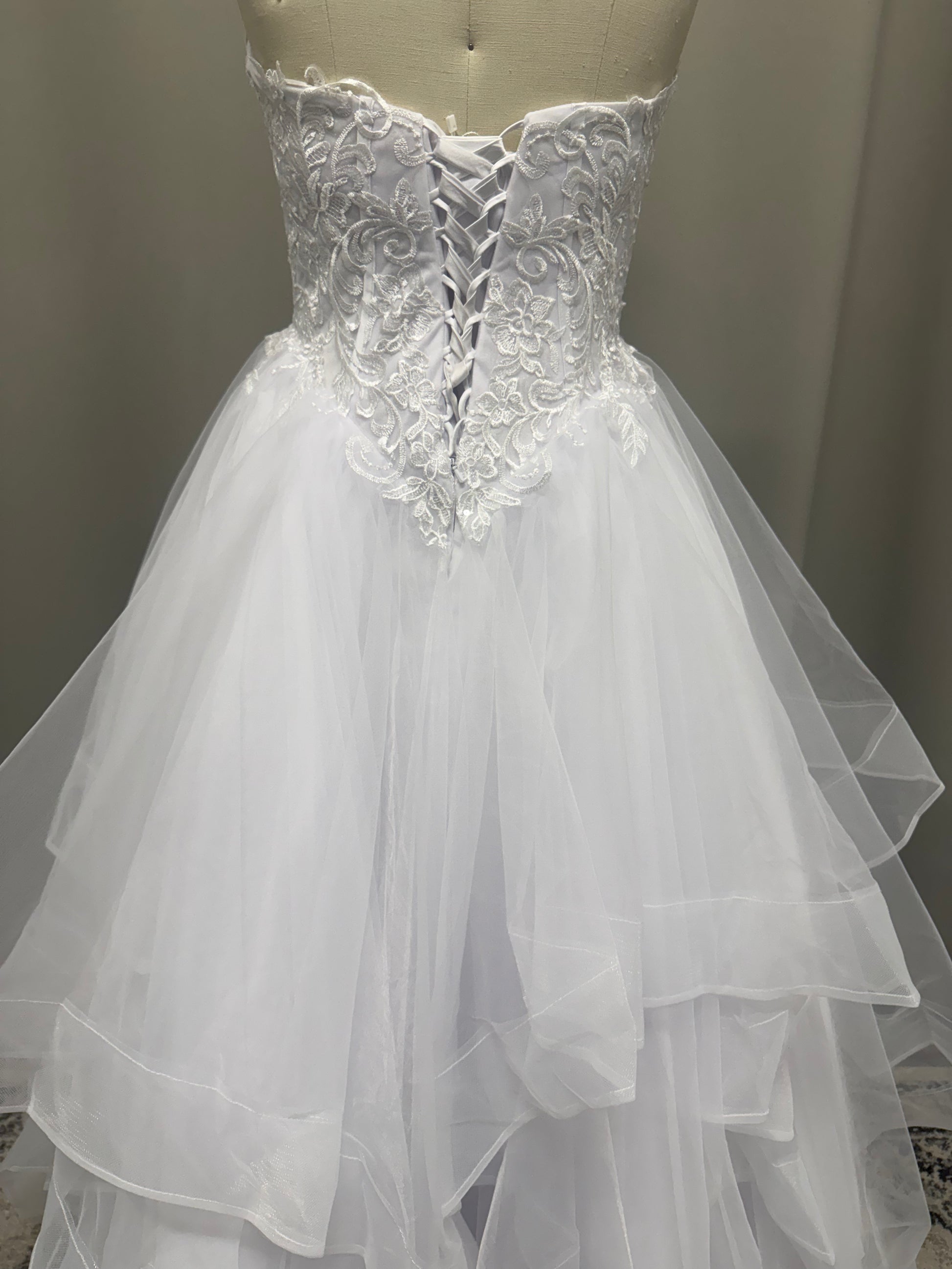 Amaira V1 floral appliqué debutante dress back view showing lace-up corset, floral lace and full white ruffle skirt