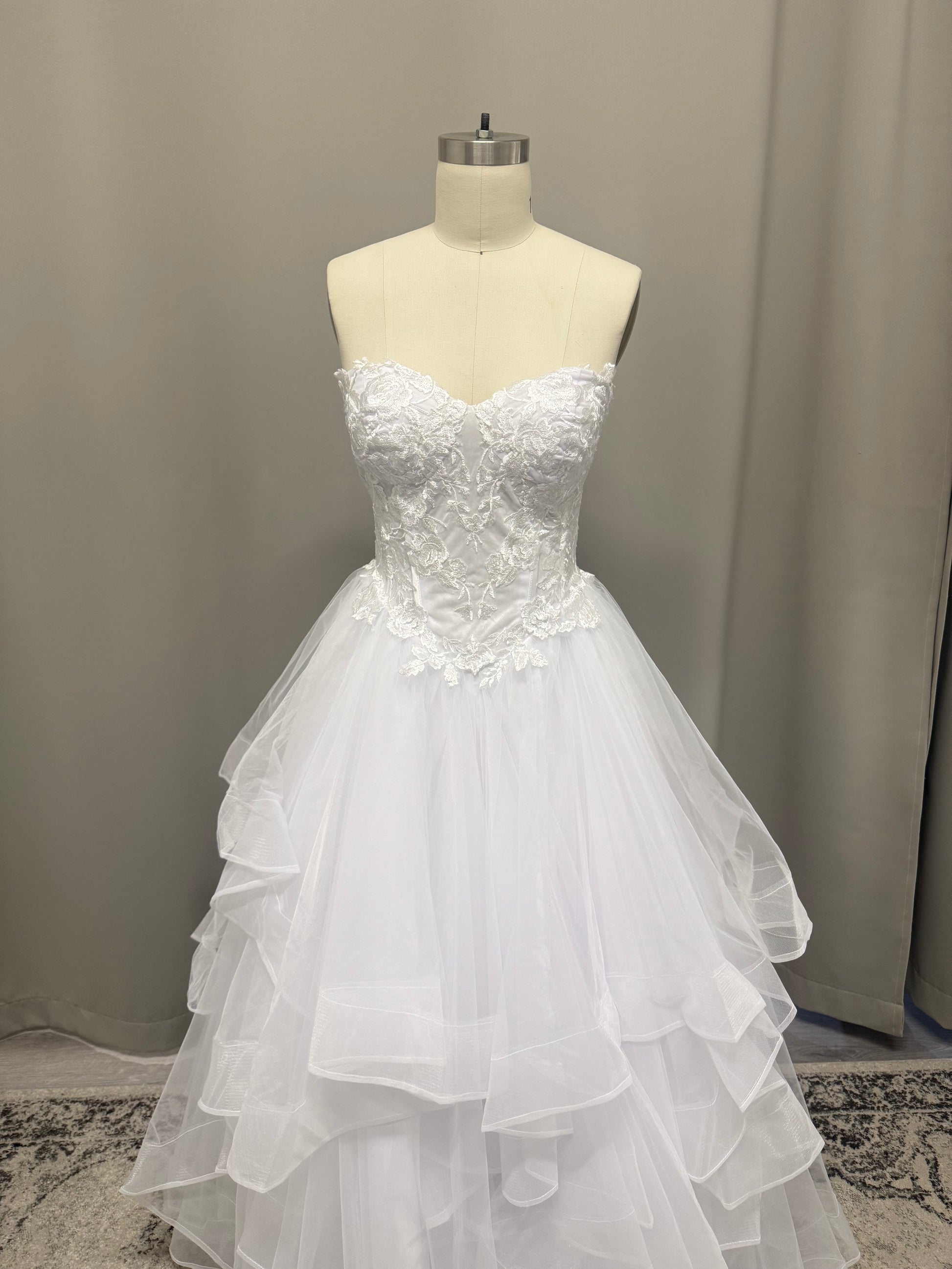 Amaira V1 white floral appliqué debutante dress, front view on mannequin with strapless lace corset and full ruffle skirt