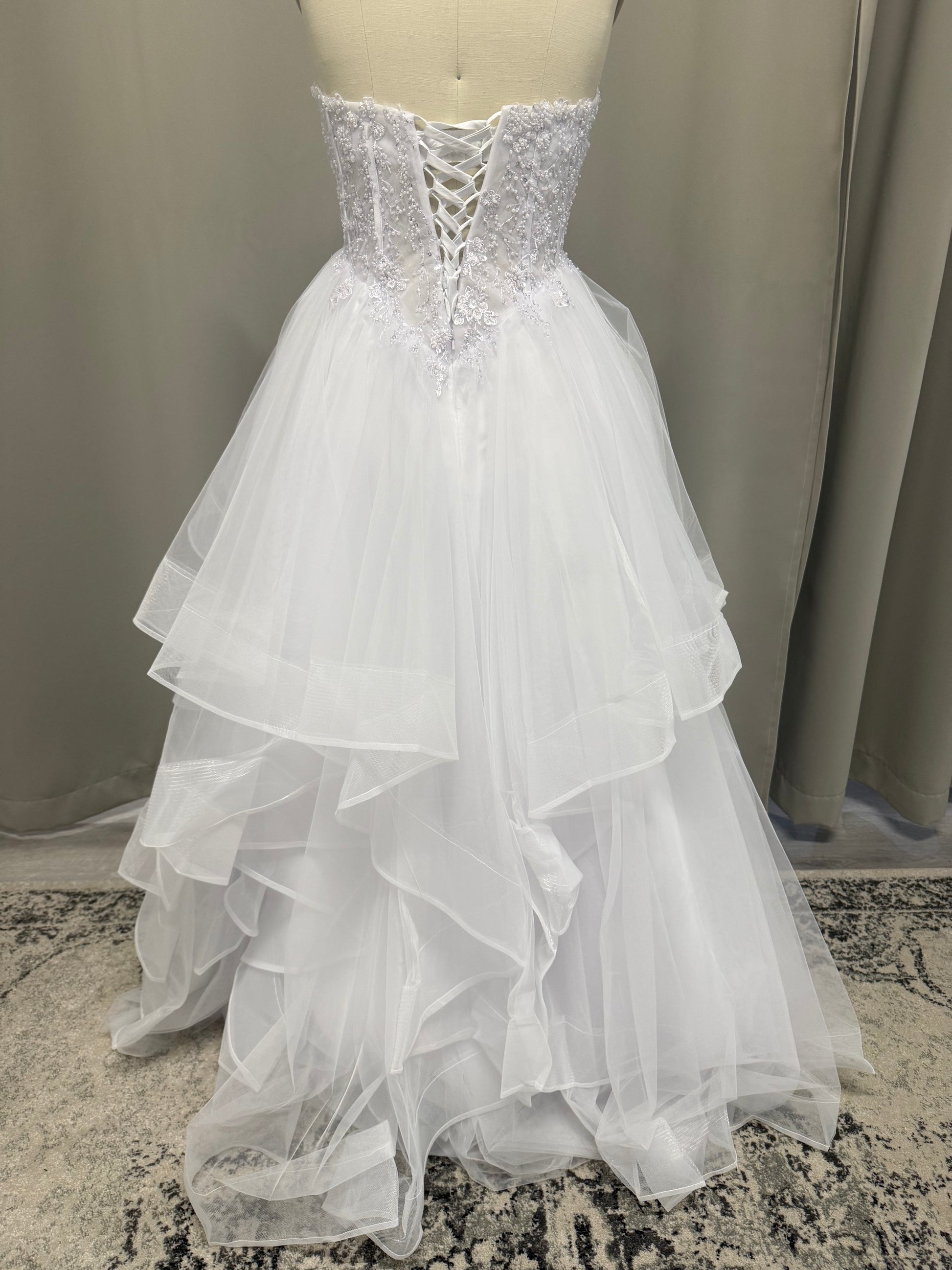 Anvi V1 beaded debutante dress back view showing lace-up corset, beaded lace and full white ruffle skirt