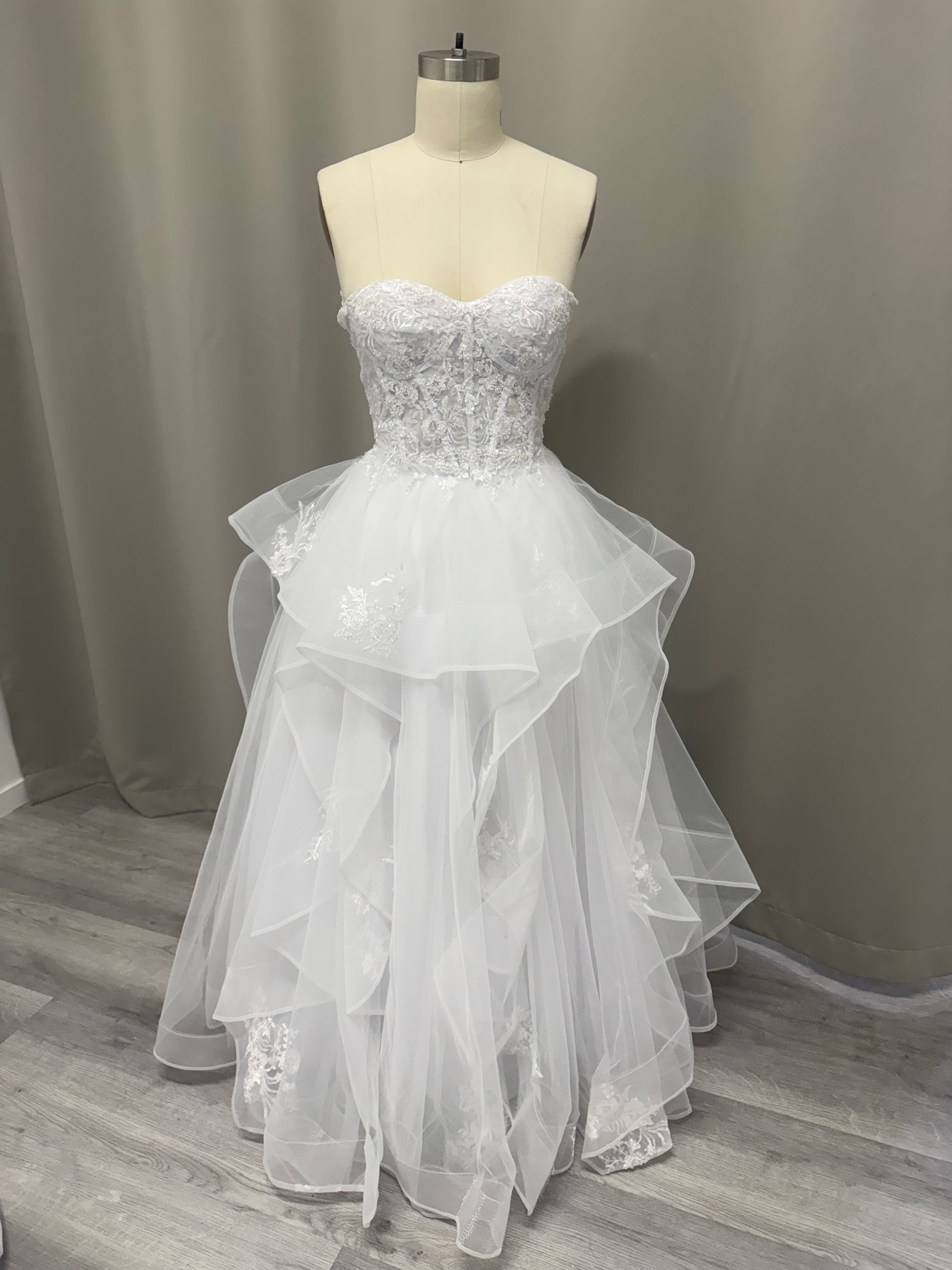 April Floral Lace Ruffled Strapless White Debutante Ball Gown on mannequin - intricate lace corset bodice and multi-layered ruffled tulle skirt