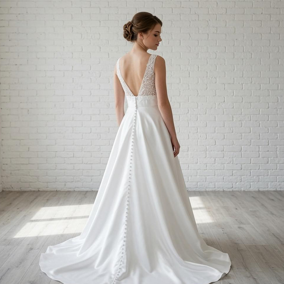 Back view of elegant white satin debutante dress featuring lace detail on the low back and button details down the skirt.