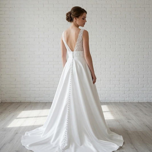 Back view of elegant white satin debutante dress featuring lace detail on the low back and button details down the skirt.