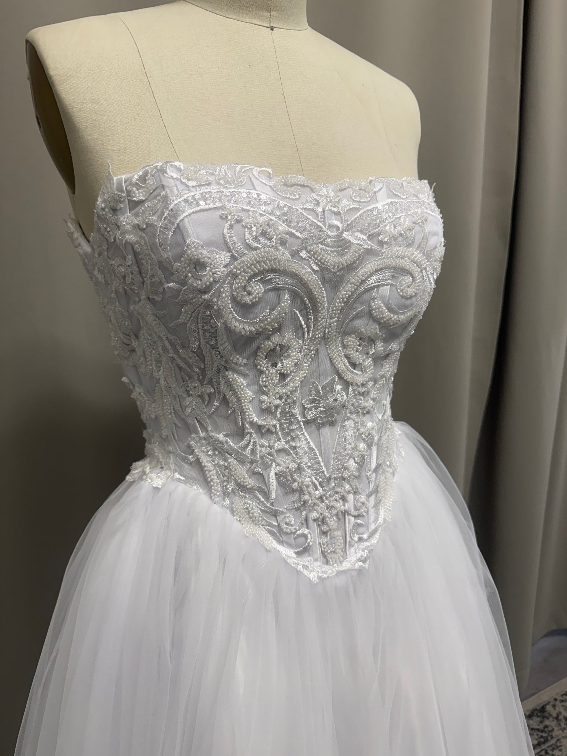 Close-up of Ava V1 scroll lace debutante dress strapless sweetheart bodice with pearl and bead detail