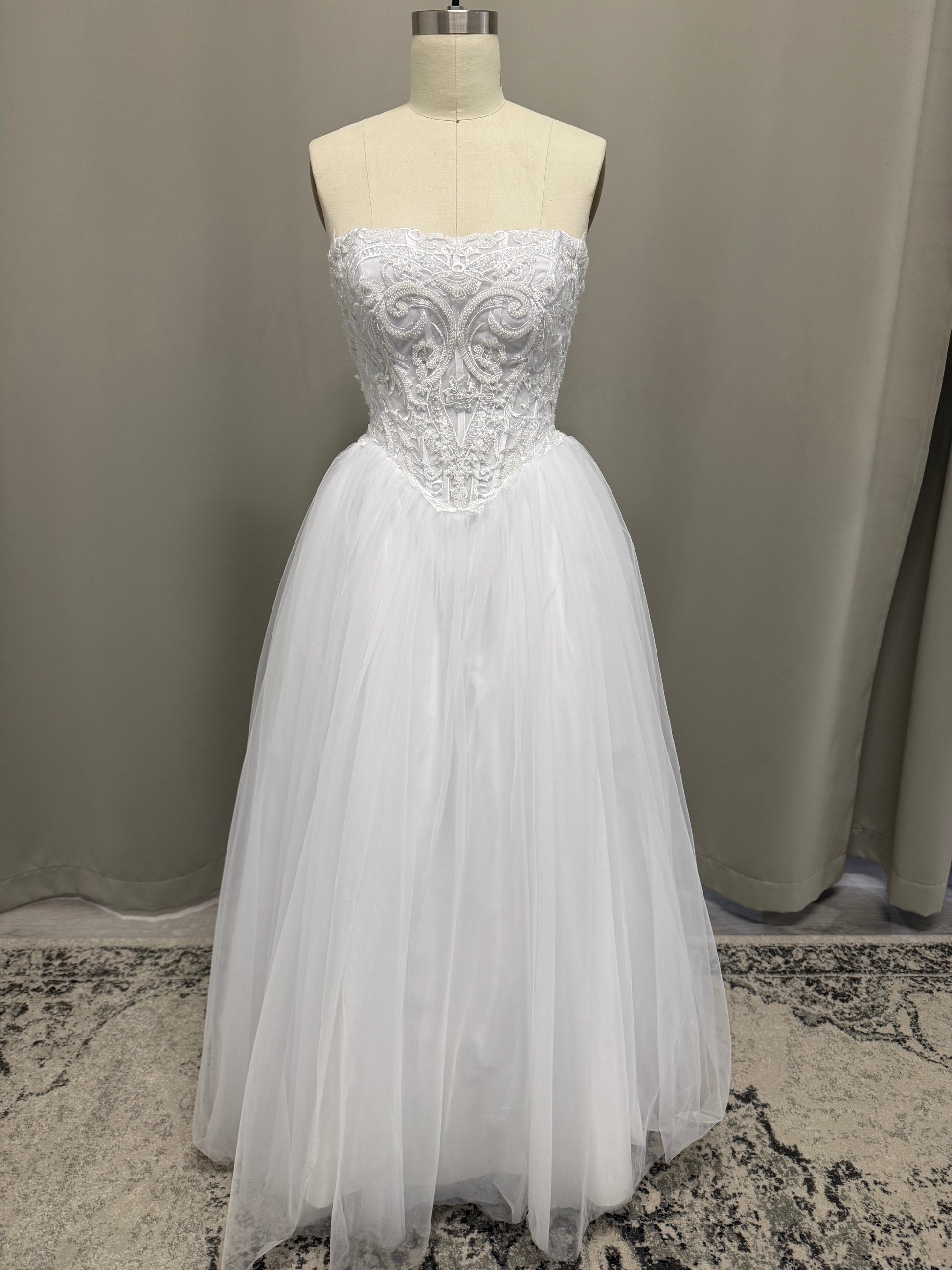 Ava V1 white scroll lace debutante dress, front view on mannequin with beaded corset and full tulle skirt