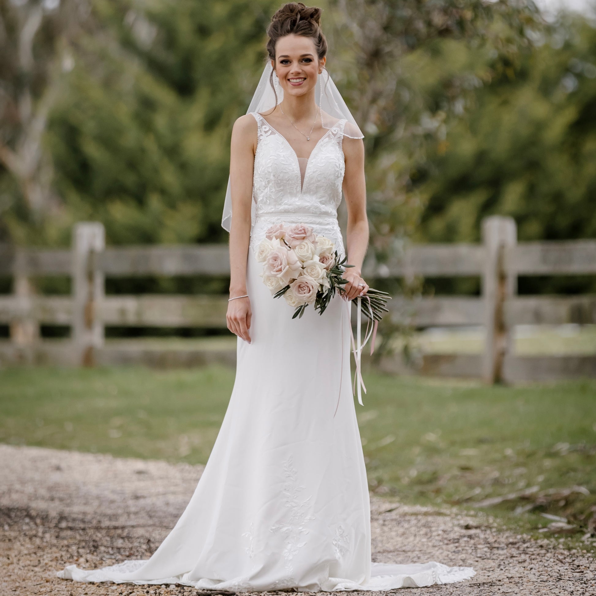 "A stunning Venus Wedding Gown inspired by the romantic charm of Venice. The gown features a plunging neckline with delicate tulle illusion insert and intricate beadwork. The fit and flare silhouette flatters the bride's curves, while lace details adorn the hem. The back showcases a V-neckline with covered buttons, and illusion skintone tulle inserts add a subtly sexy touch. The gown is completed with a chapel train, creating a breathtaking bridal look."