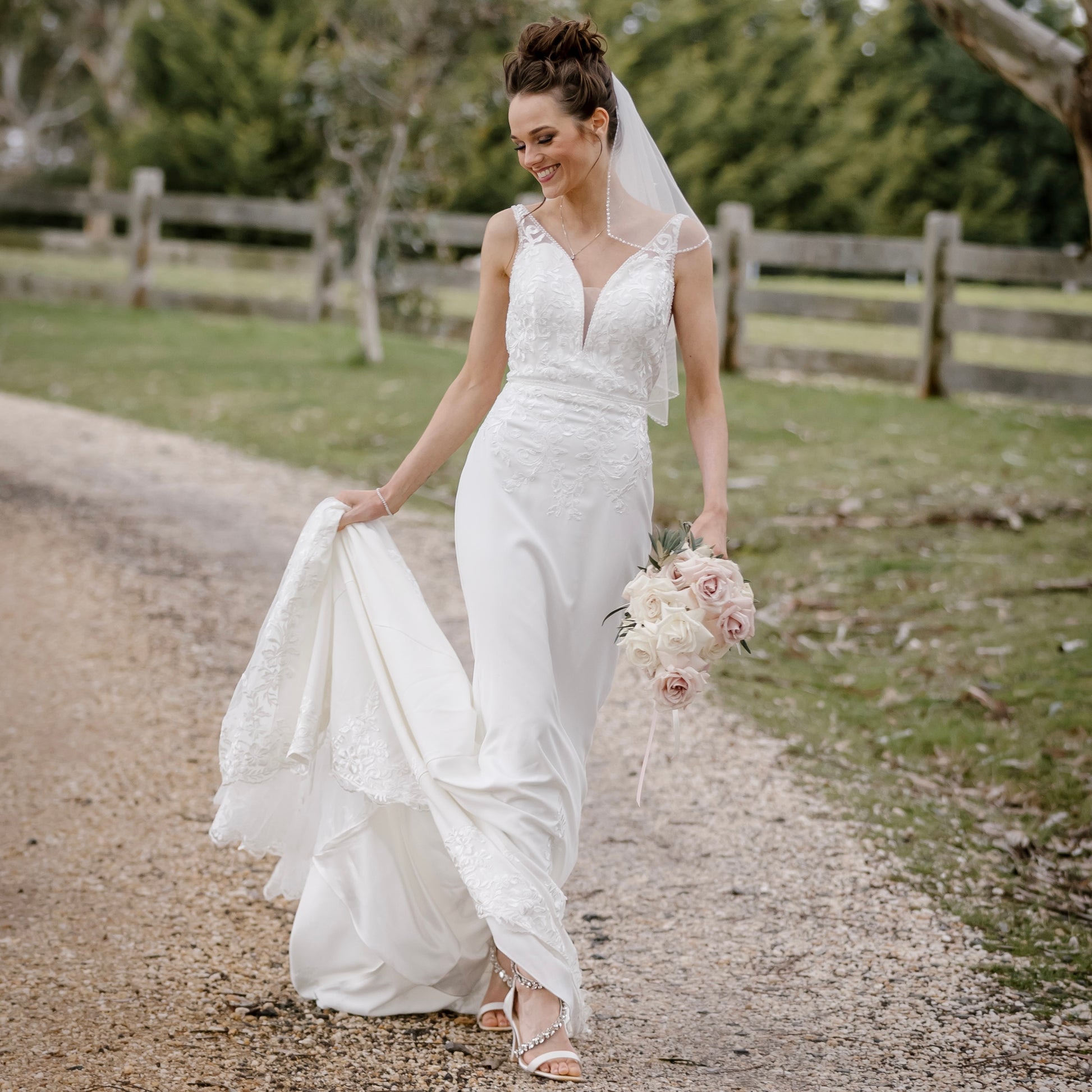 "A stunning Venus Wedding Gown inspired by the romantic charm of Venice. The gown features a plunging neckline with delicate tulle illusion insert and intricate beadwork. The fit and flare silhouette flatters the bride's curves, while lace details adorn the hem. The back showcases a V-neckline with covered buttons, and illusion skintone tulle inserts add a subtly sexy touch. The gown is completed with a chapel train, creating a breathtaking bridal look."