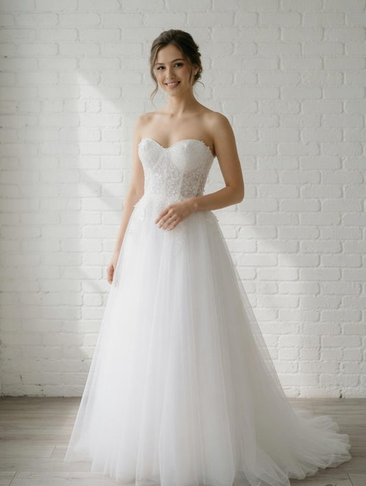Elegant white strapless debutante dress with sweetheart neckline, intricately detailed floral lace bodice, and flowing full tulle skirt.