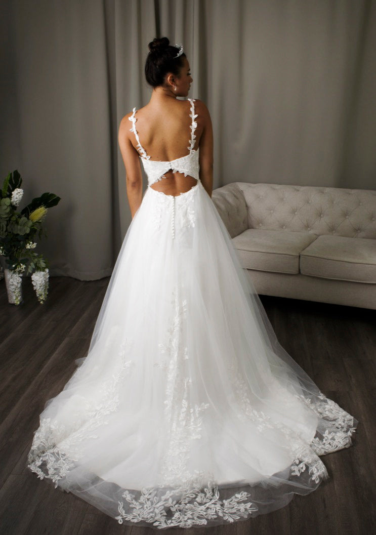 Bride in Holly, a floral leaf lace adorned A-line bridal gown with deep V-neckline, lace straps, and a keyhole back.