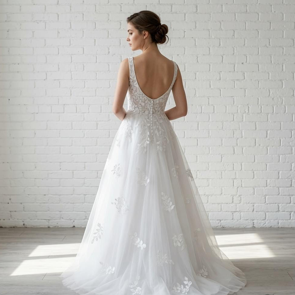 Back view of elegant white sleeveless debutante dress with deep scoop back and cascading floral lace details on the full tulle skirt.