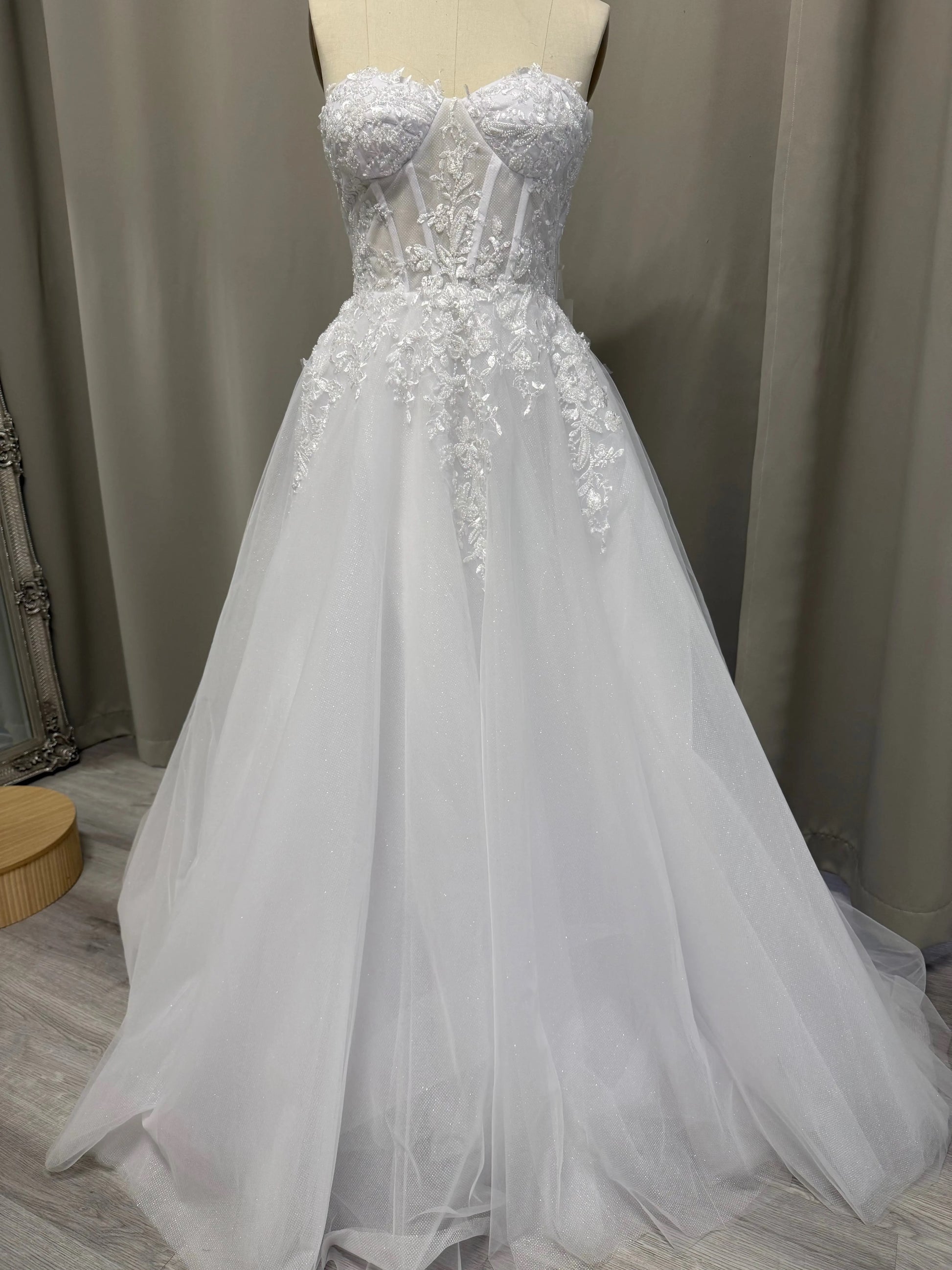 White debutante dress on a mannequin against a neutral background