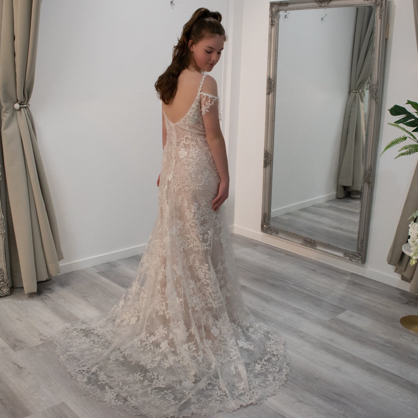 Bride in Koral wedding gown, showcasing the V-neckline, lace detailing, and the enchanting train.