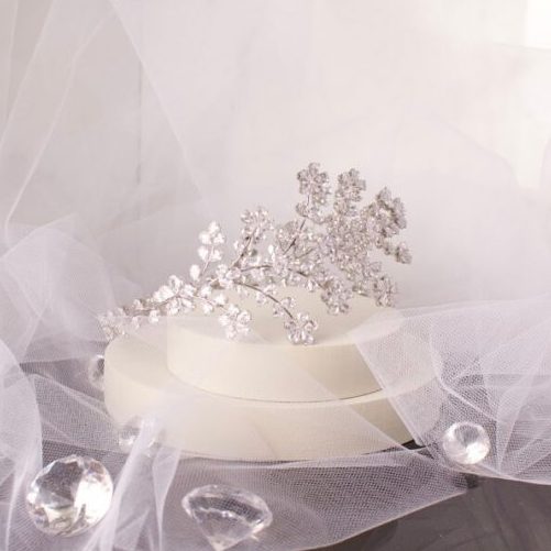 Elegant Lena Bridal Tiara with shimmering floral blossoms and silver crystal CZ embellished leaves, cascading delicately over the side of the headband, perfect for a glamorous bridal hairstyle.