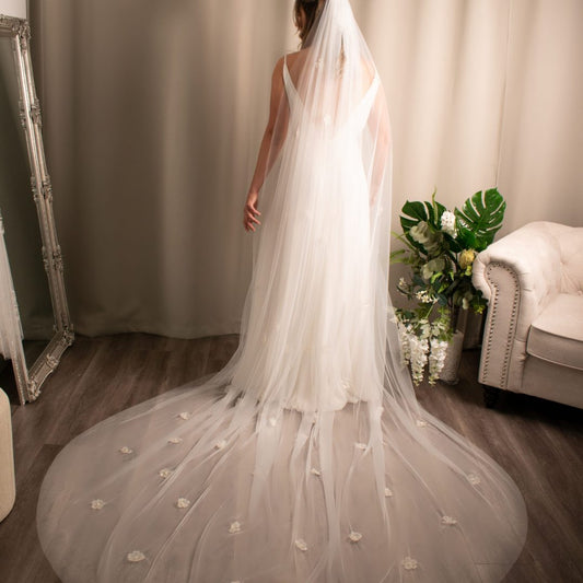 Bella Flower Pearl Veil in soft tulle with intricate floral appliqués and central pearl accents, symbolizing a blend of nature and bridal grace.
