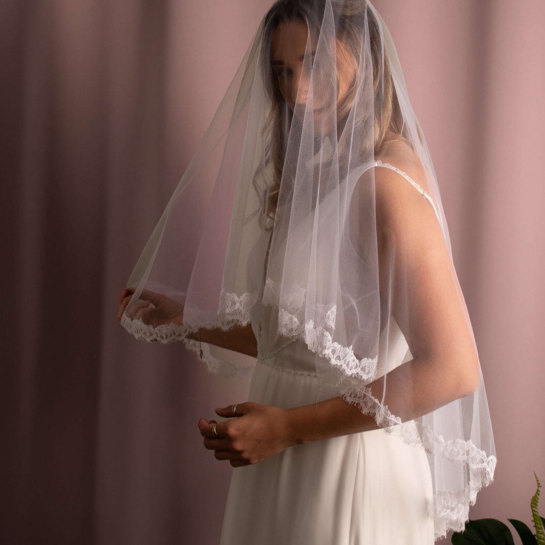Elliott Lace Trim Veil in fingertip length with lace edging, made of soft American tulle, draped elegantly over the face.