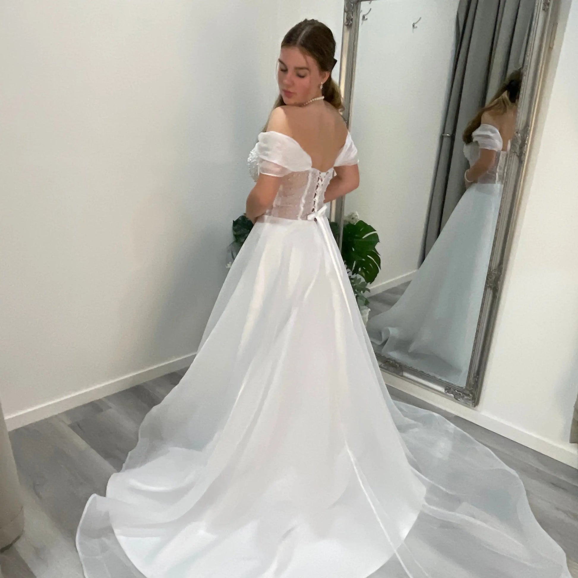 Side-back view of Diana Debutante Dress highlighting the lace corset bodice, supportive straps, and the ethereal organza A-line skirt that creates a graceful silhouette.