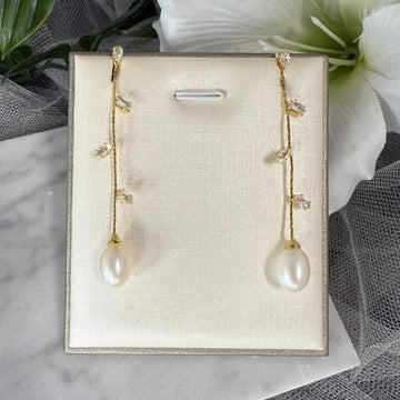 Pair of silver earrings with teardrop-shaped gemstones on a beige display card.