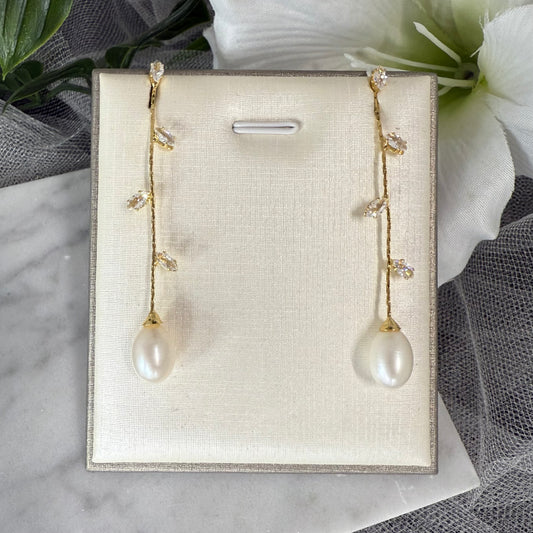 Pair of silver earrings with teardrop-shaped gemstones on a beige display card.
