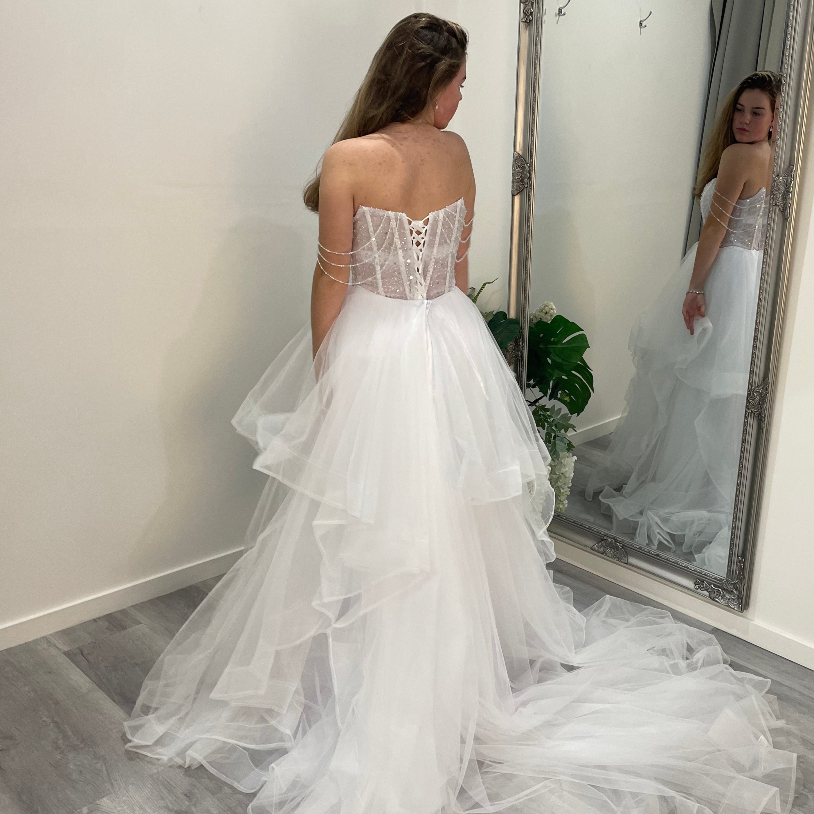 Back view of Elowen Debutante Dress showcasing beaded dangling straps and a full, flowing tulle skirt with ruffled waist detailing.