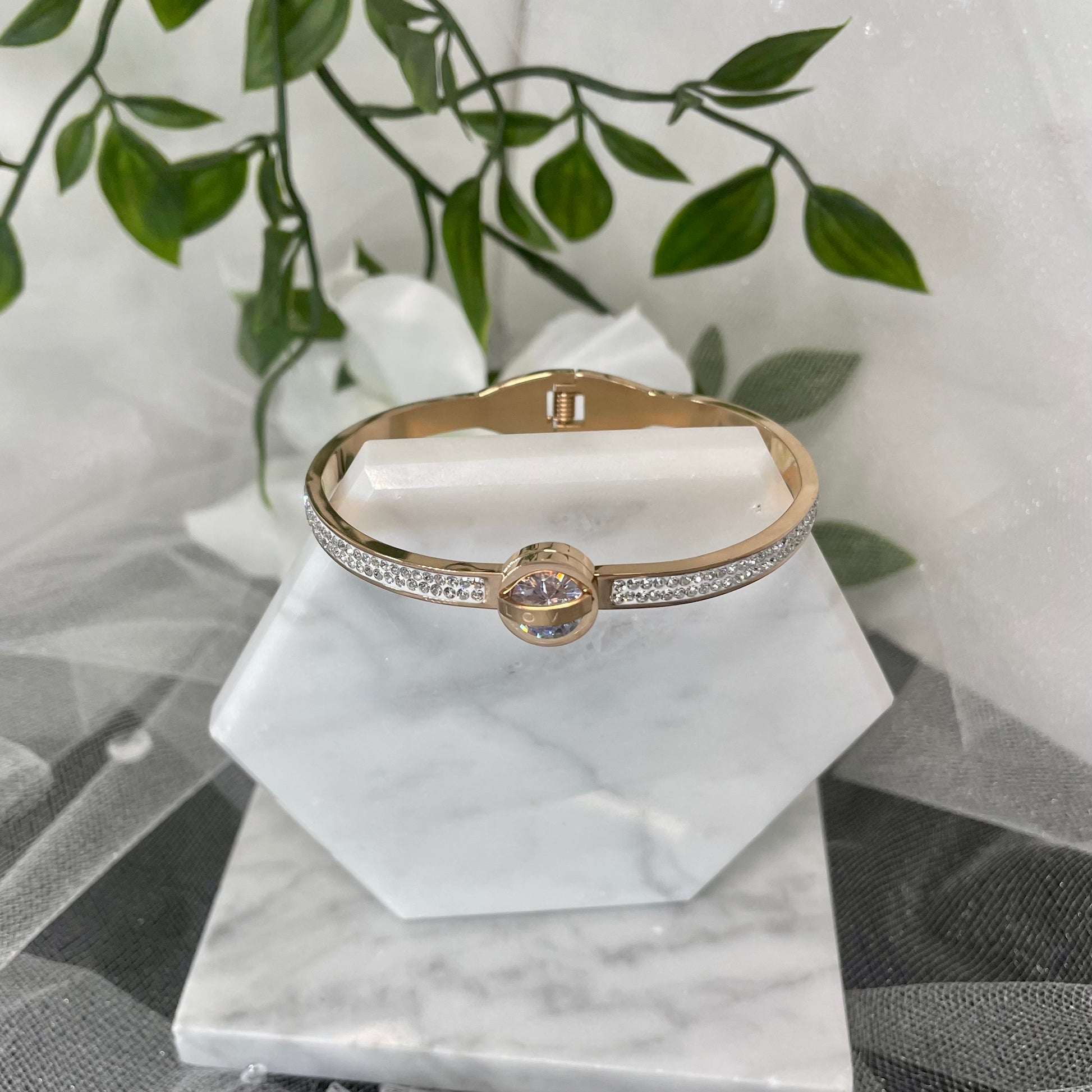 18k Rose Gold Plated CZ Bracelet with 'Love' inscribed on the center round crystal, displayed on a velvet cushion.
