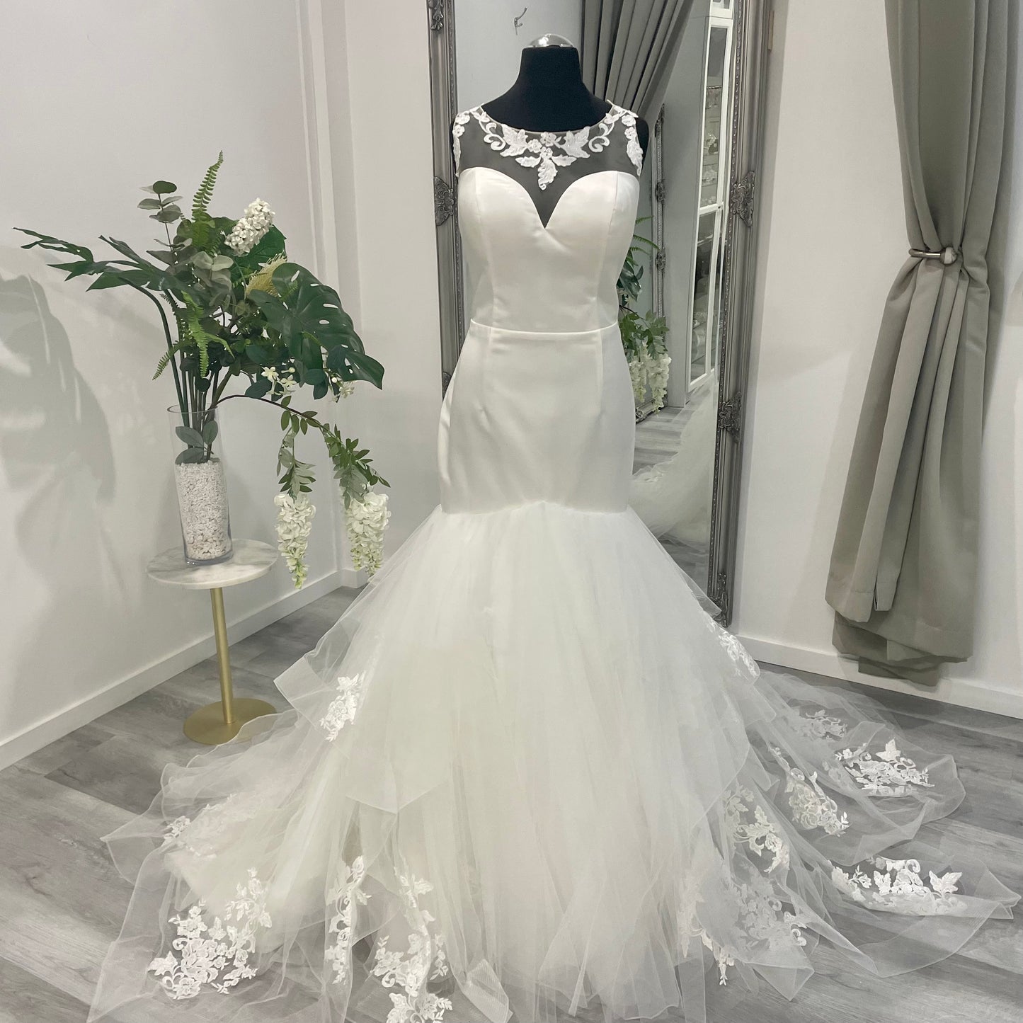 Chic Iris Trumpet bridal gown with intricate lace detailing and a flowing mermaid silhouette on display at Divine Bridal.
