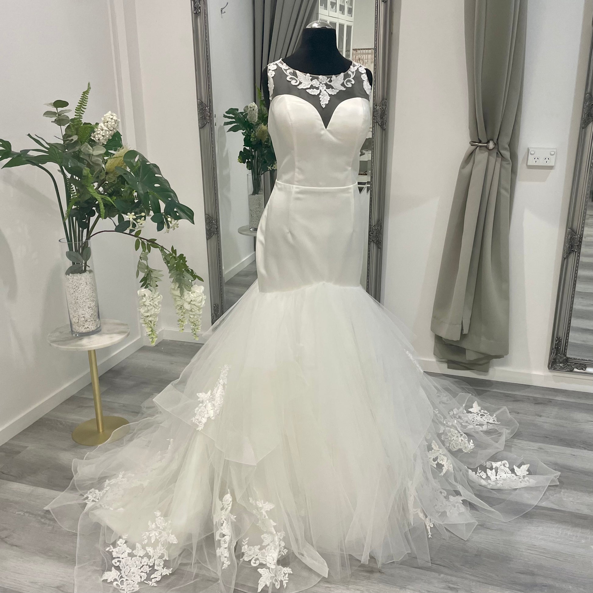 Chic Iris Trumpet bridal gown with intricate lace detailing and a flowing mermaid silhouette on display at Divine Bridal.
