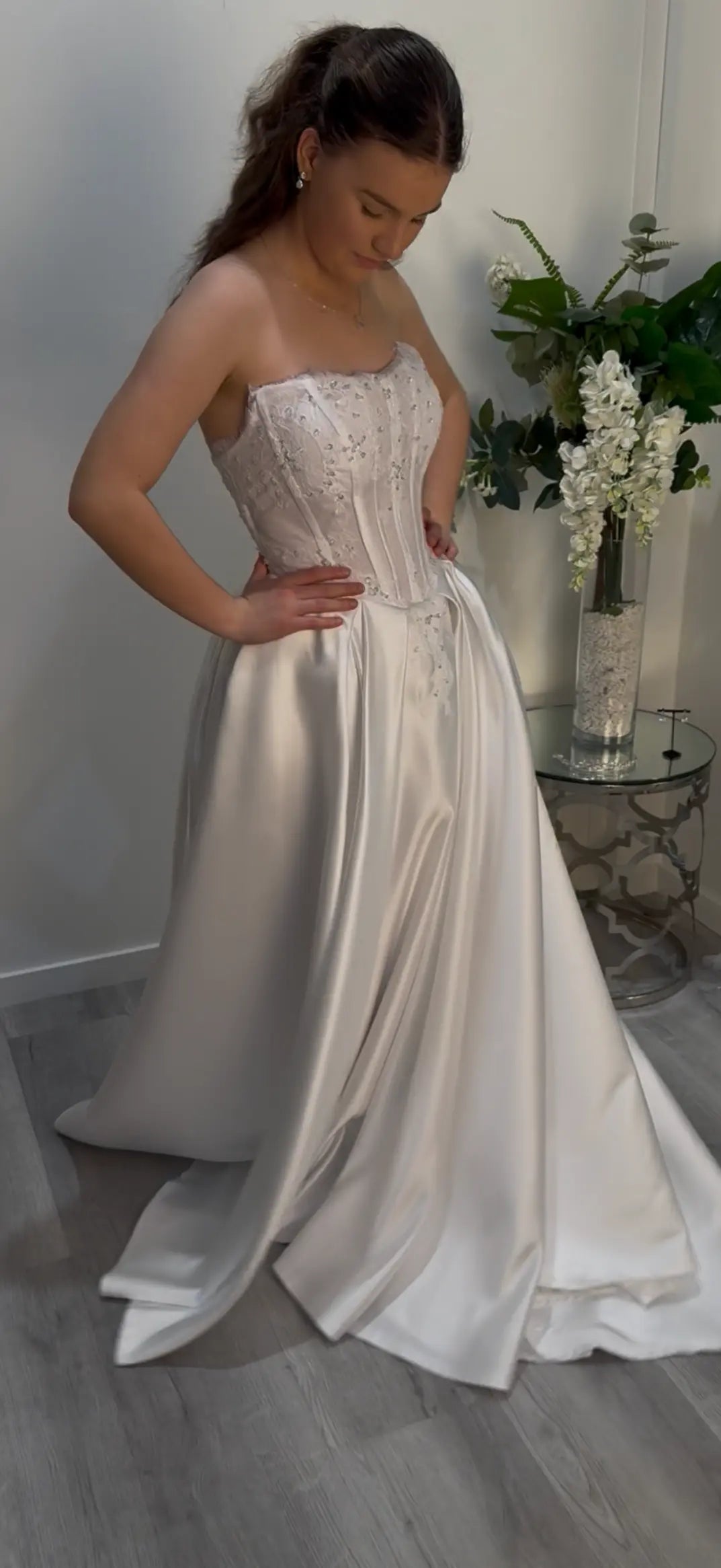 Girl wearing a strapless white Deb dress looking down showing the side of the dress.