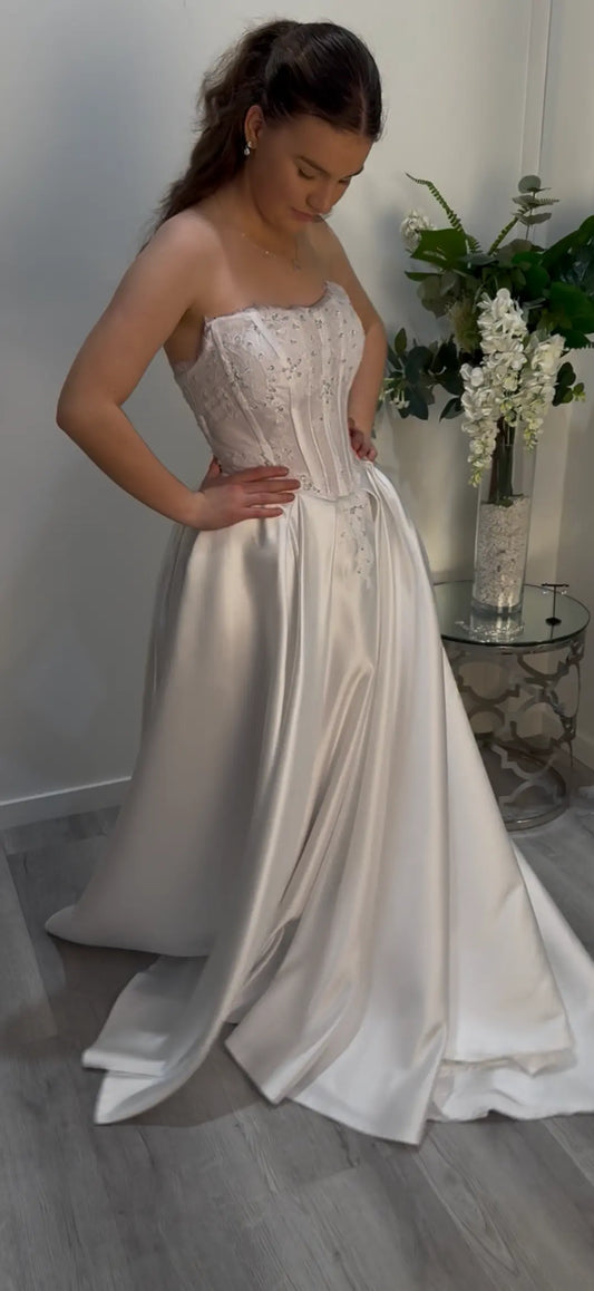 Girl wearing a strapless white Deb dress looking down showing the side of the dress.