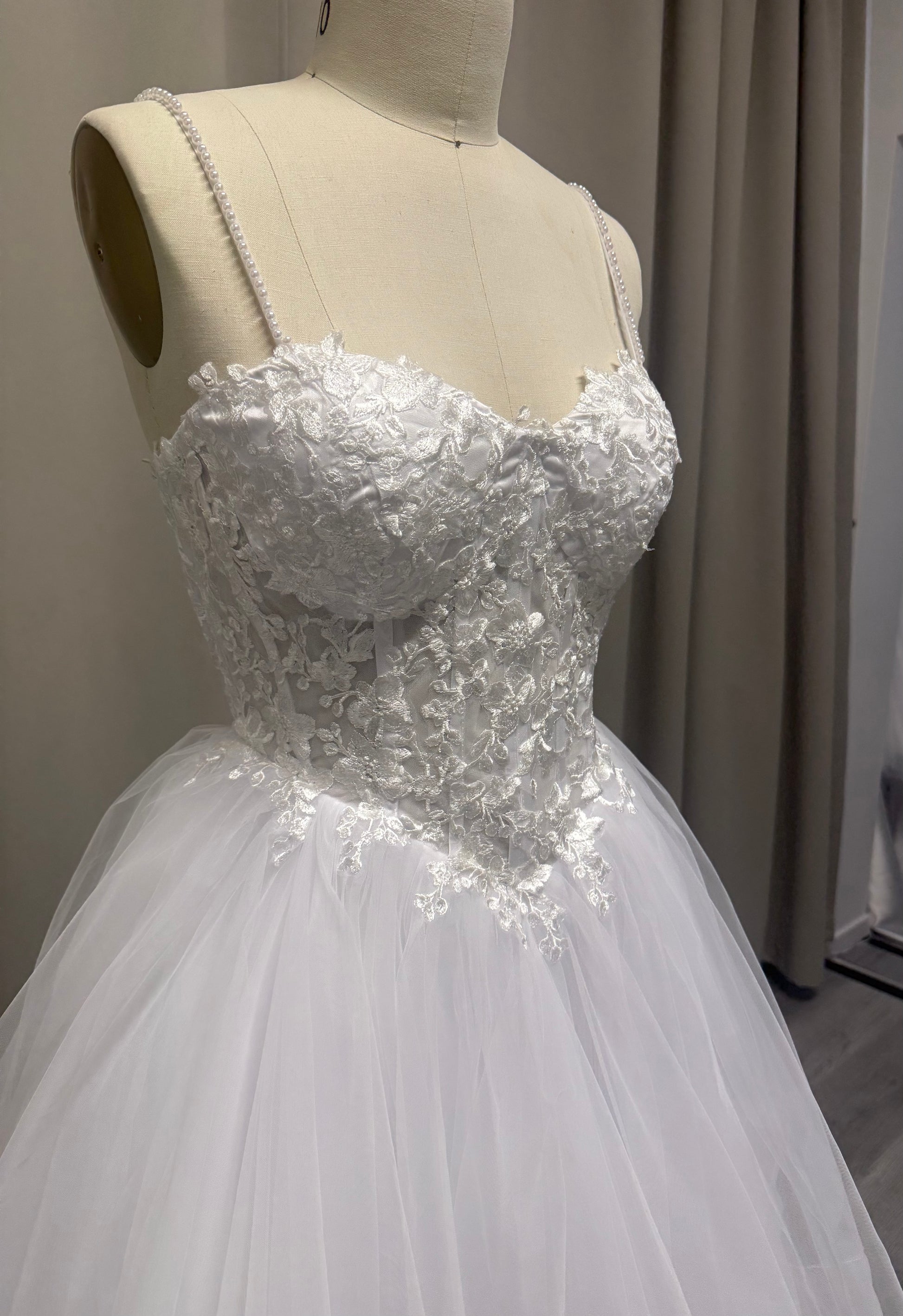 Close-up of Riva debutante dress sweetheart lace bodice with floral appliqué and pearl spaghetti straps