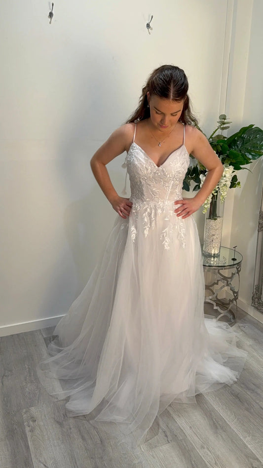 Woman wearing a white debutante dress with intricate detailing in a room.
