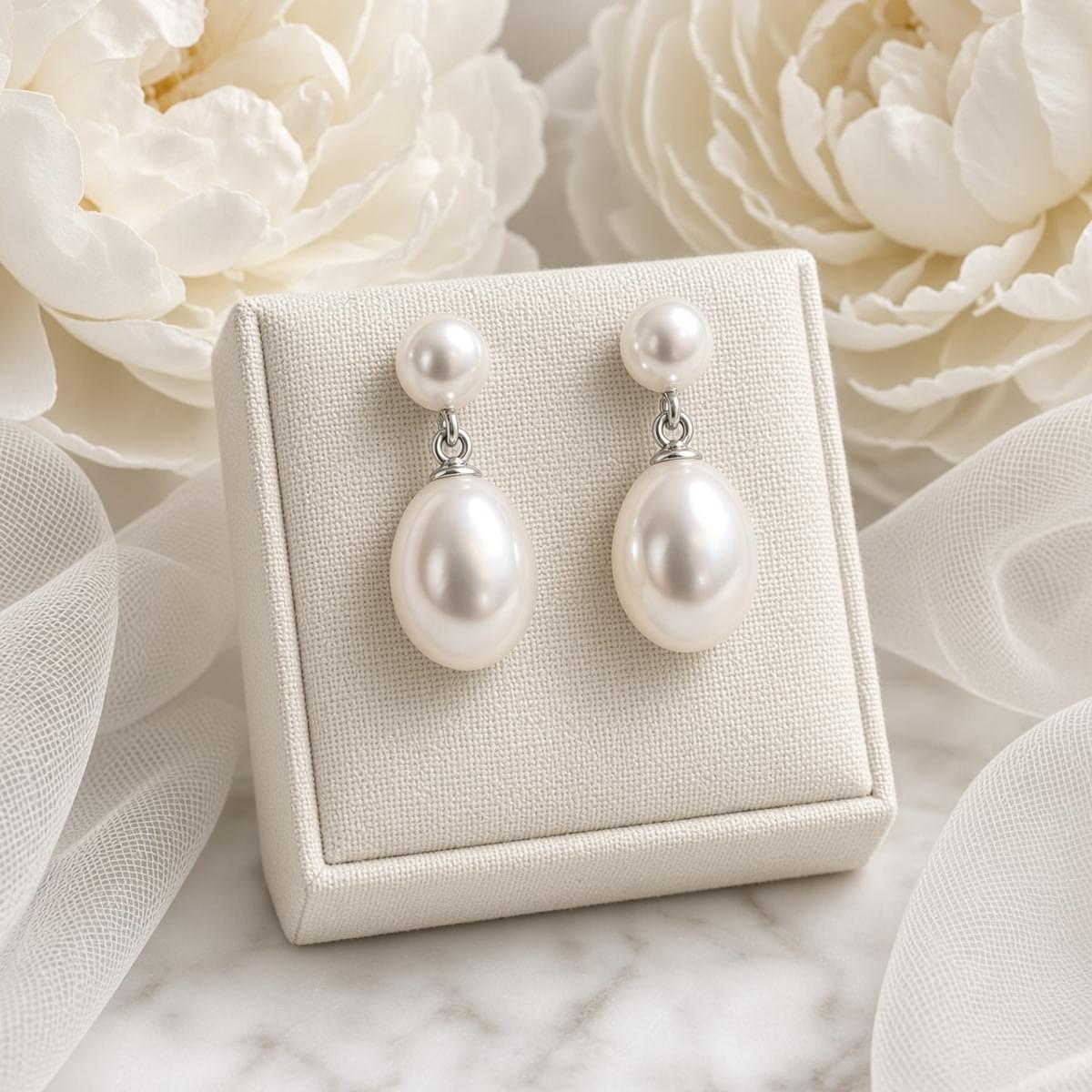 Natural white freshwater pearl earrings on white display with flowers – bridal earrings