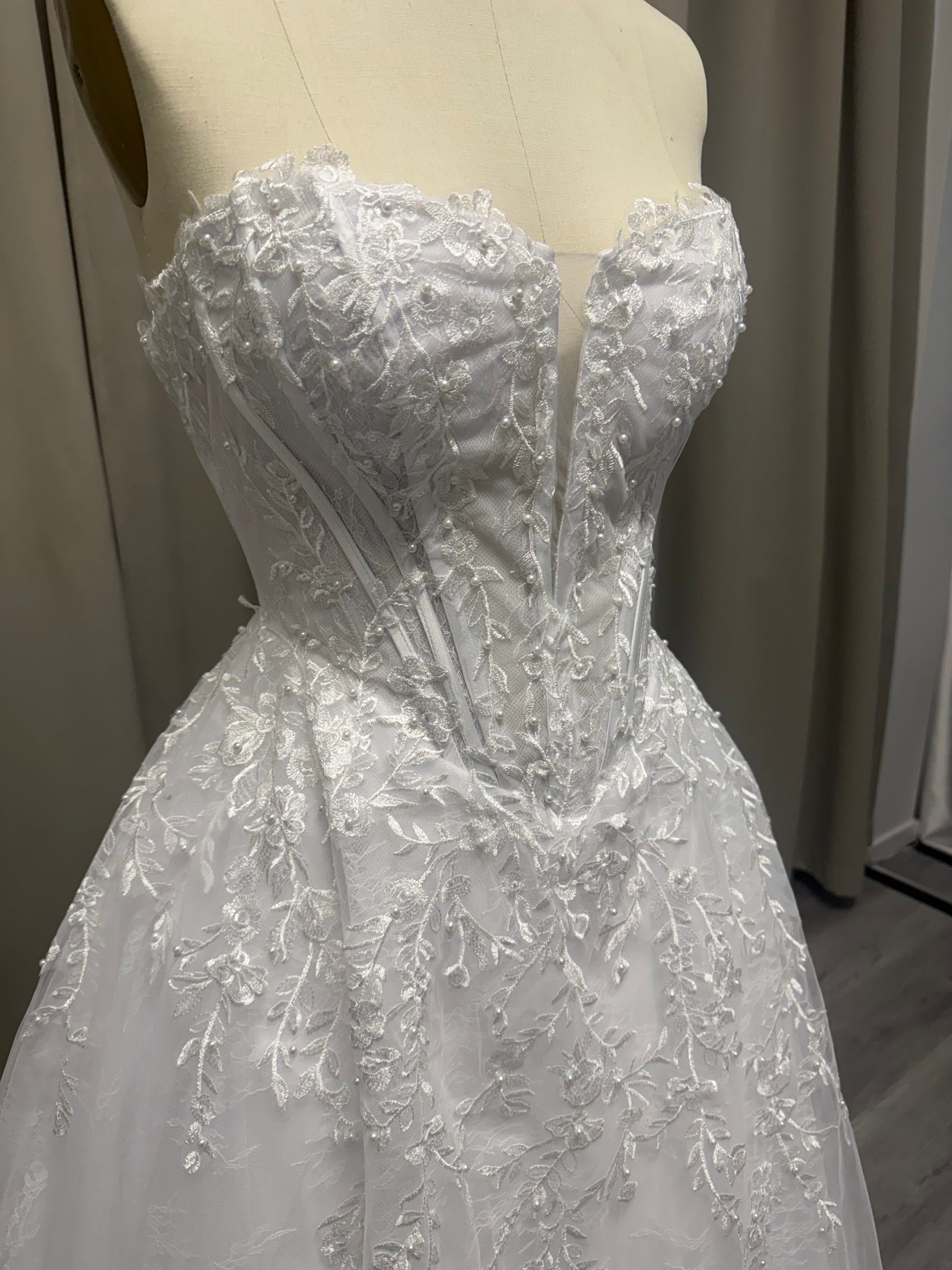 Close-up of Lilly deb ball dress strapless sweetheart bodice with floral lace, pearl detailing and structured corset