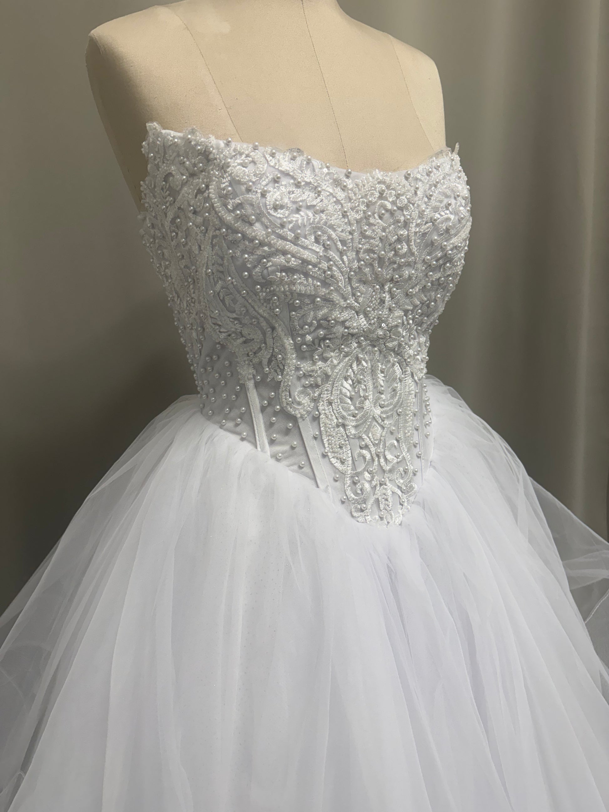 Close-up of Loretta V1 pearl debutante dress strapless sweetheart bodice with pearl and scroll lace appliqué
