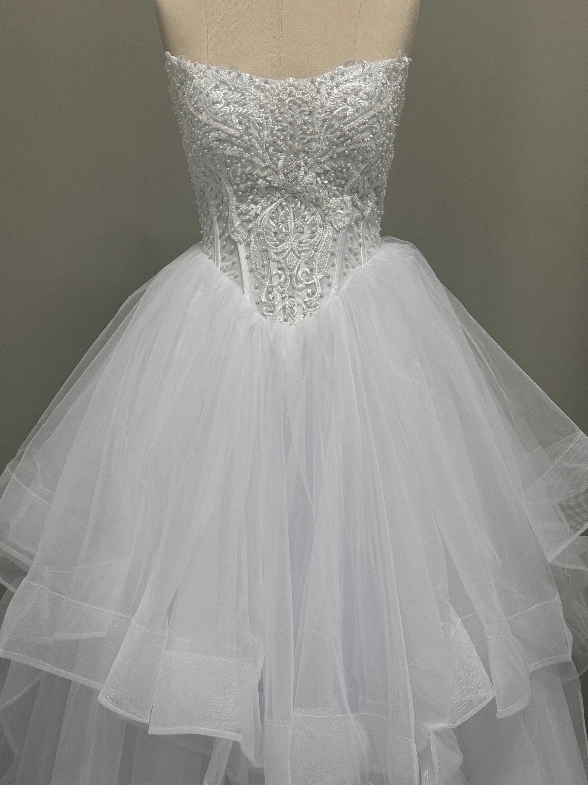 Loretta V1 white pearl debutante dress, front view on mannequin with lace corset and full ruffle skirt