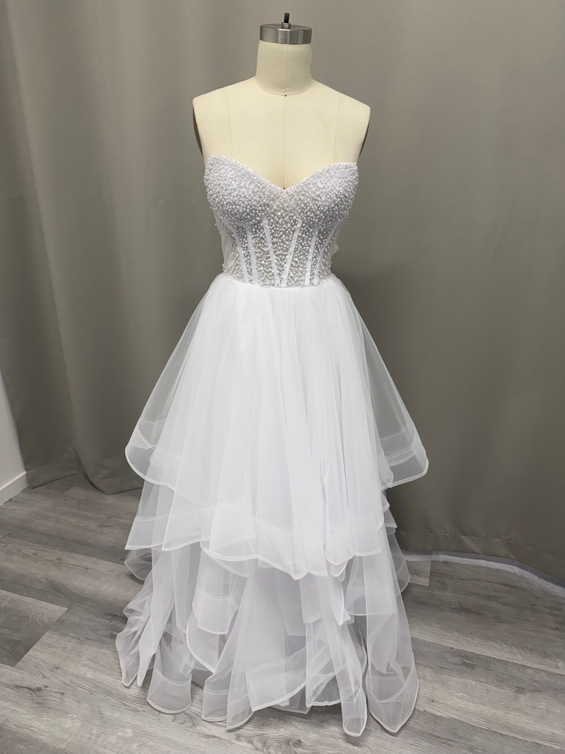 Lyra Ruffled Pearl Beaded Strapless Debutante Ball Gown on mannequin - white pearl beaded corset with multi-layered ruffled tulle skirt
