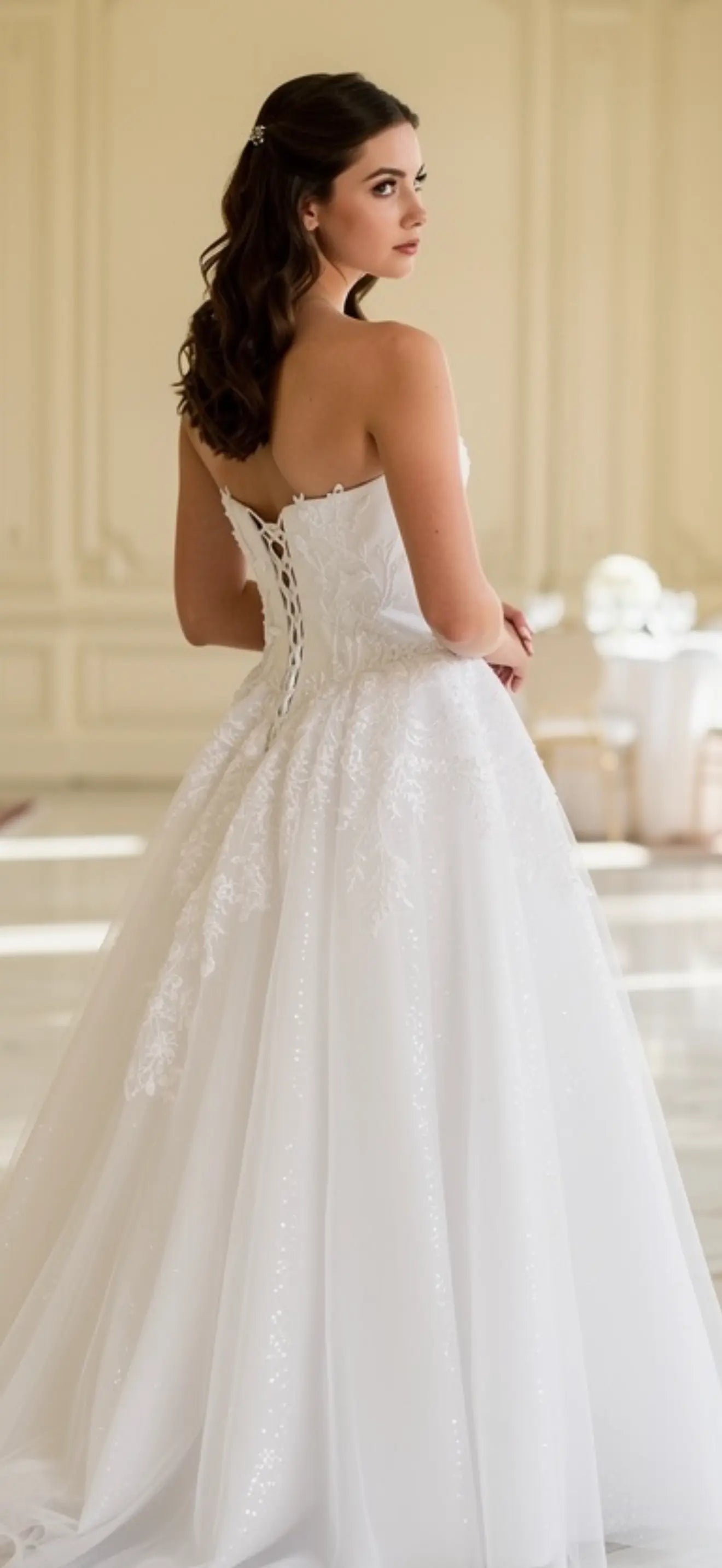 Woman in a white debutante dress standing in a elegant room.