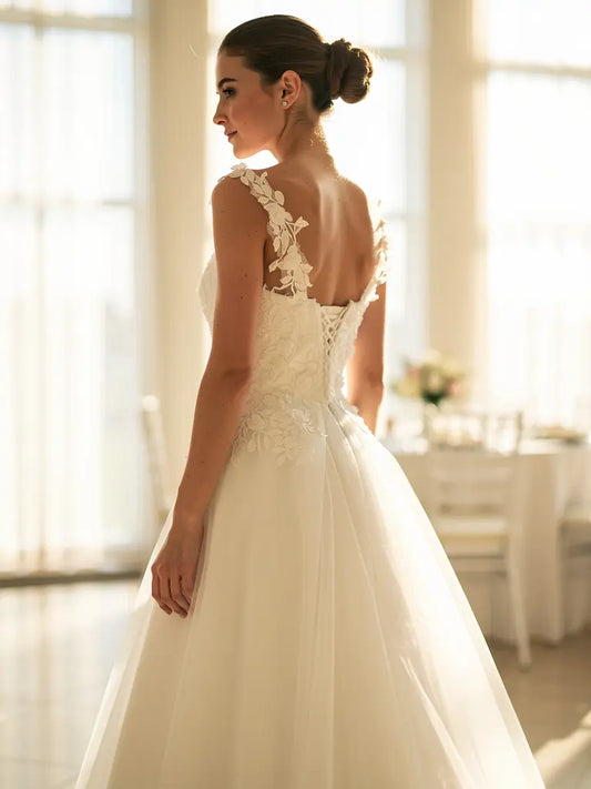 Woman wearing a white debutante dress with floral details in a softly lit room.