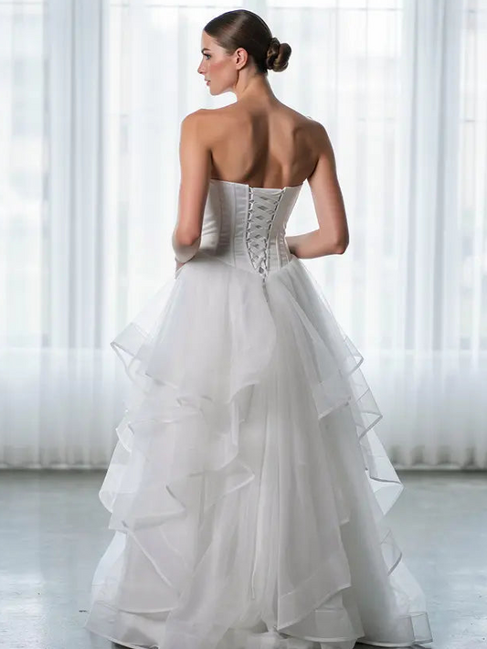 Woman wearing a strapless white deb dress with ruffled layers in a bright room.